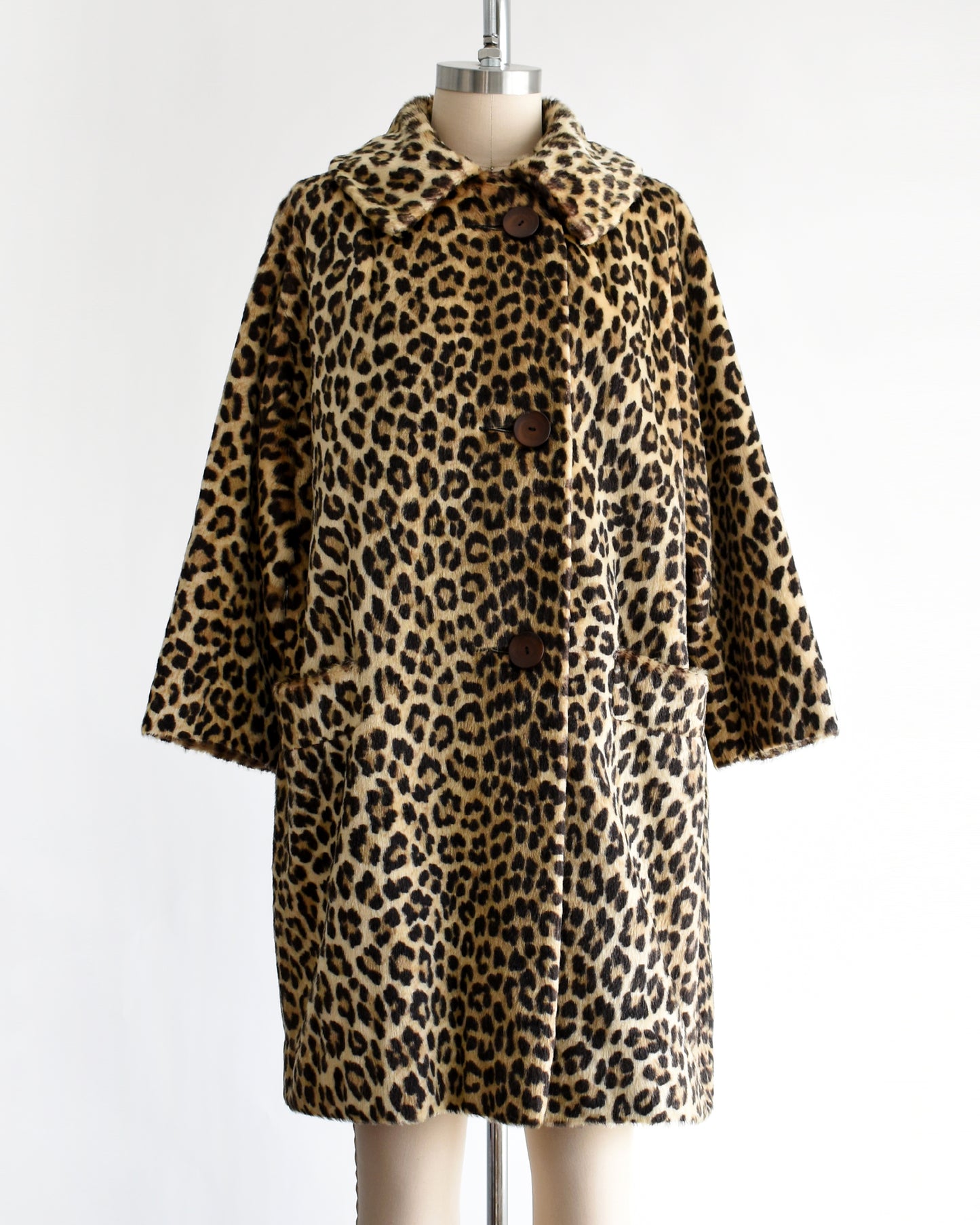 a vintage 1960s faux fur leopard print coat on a dress form against a white background