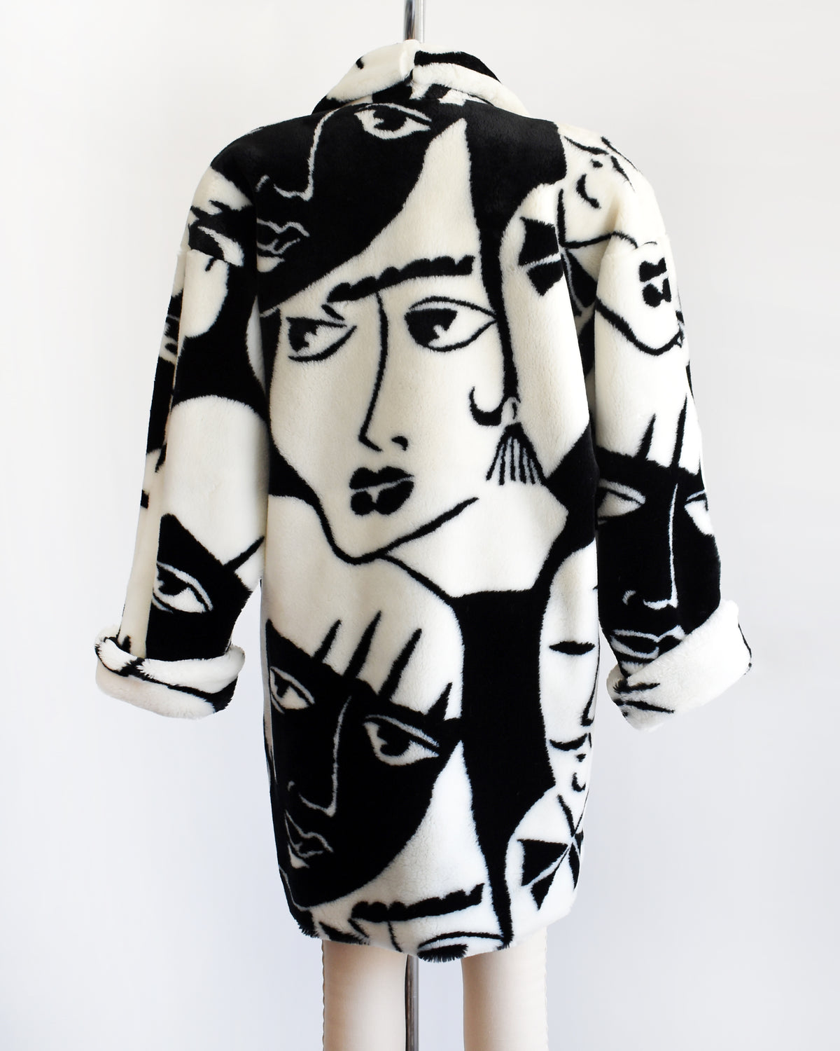 back view of a vintage 1980s Donnybrook black and white graphic face patterned plush coat displayed on a mannequin against a plain white background.