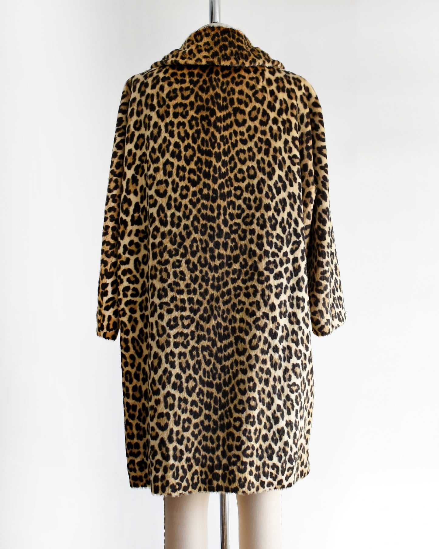 back view of a vintage 1960s faux fur leopard print coat on a dress form against a white background