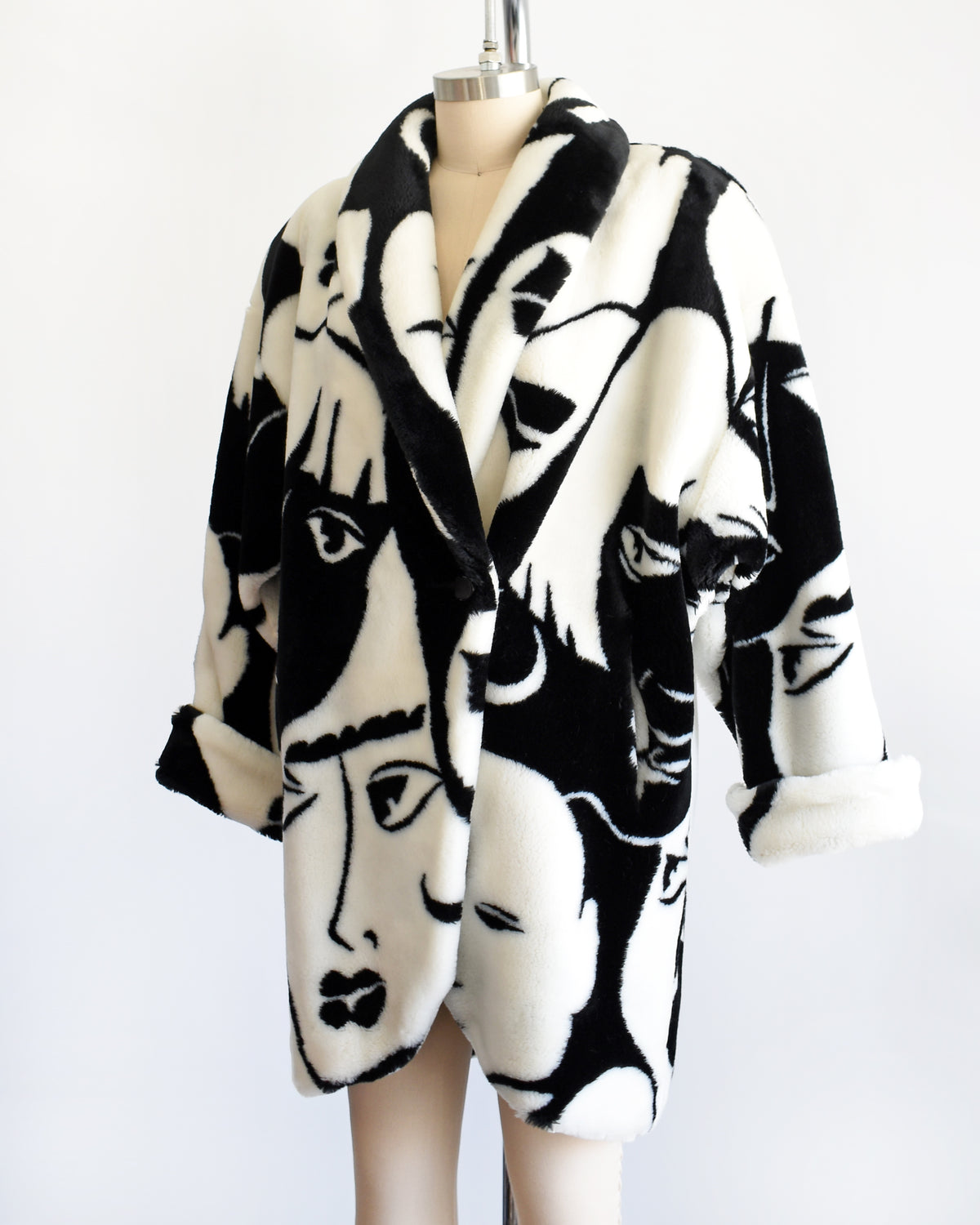 side front view of a vintage 1980s Donnybrook black and white graphic face patterned plush coat displayed on a mannequin against a plain white background.