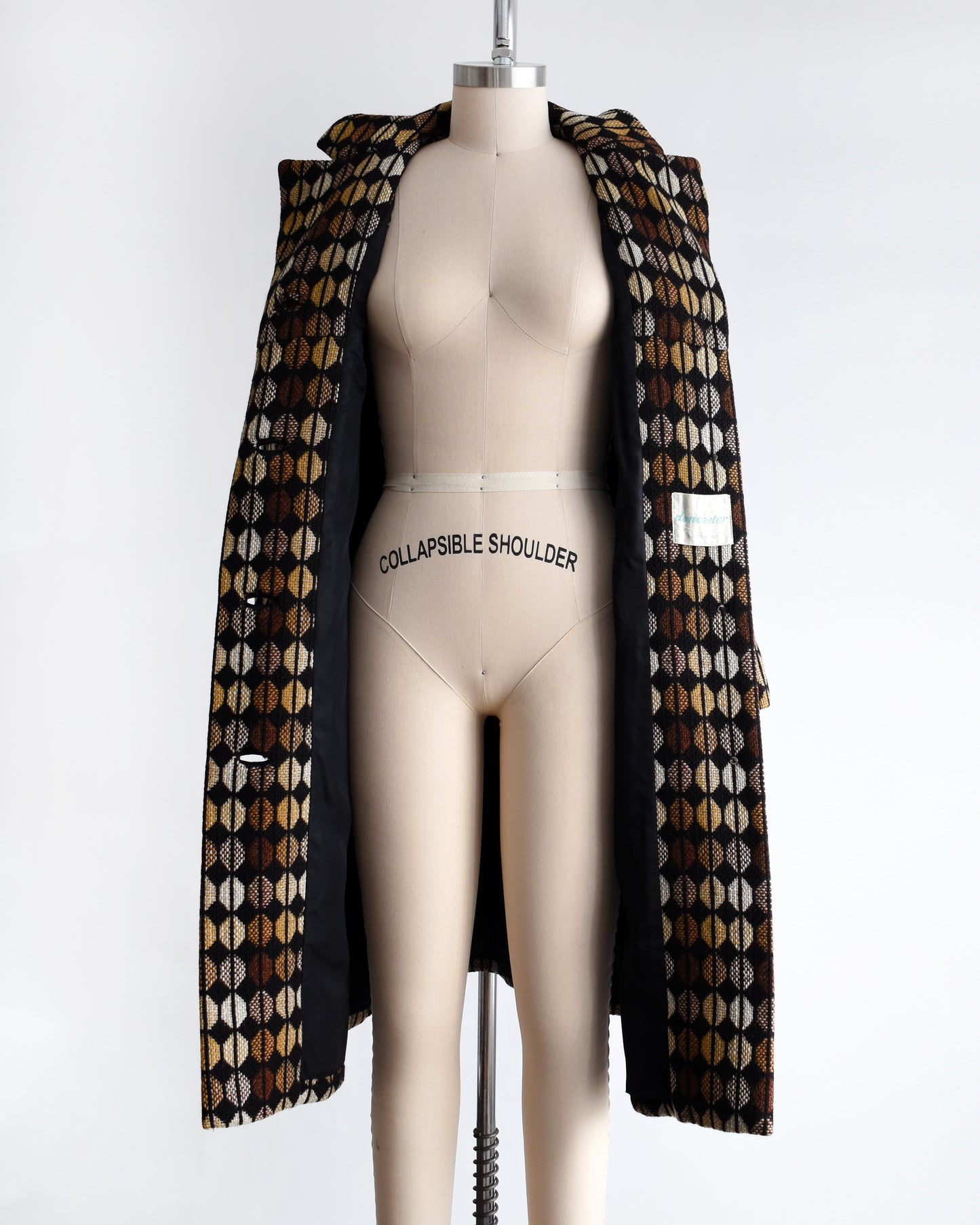 a vintage 1970s black and brown patterned coat on a mannequin against a white background. the coat is opened in this photo showing the black lining
