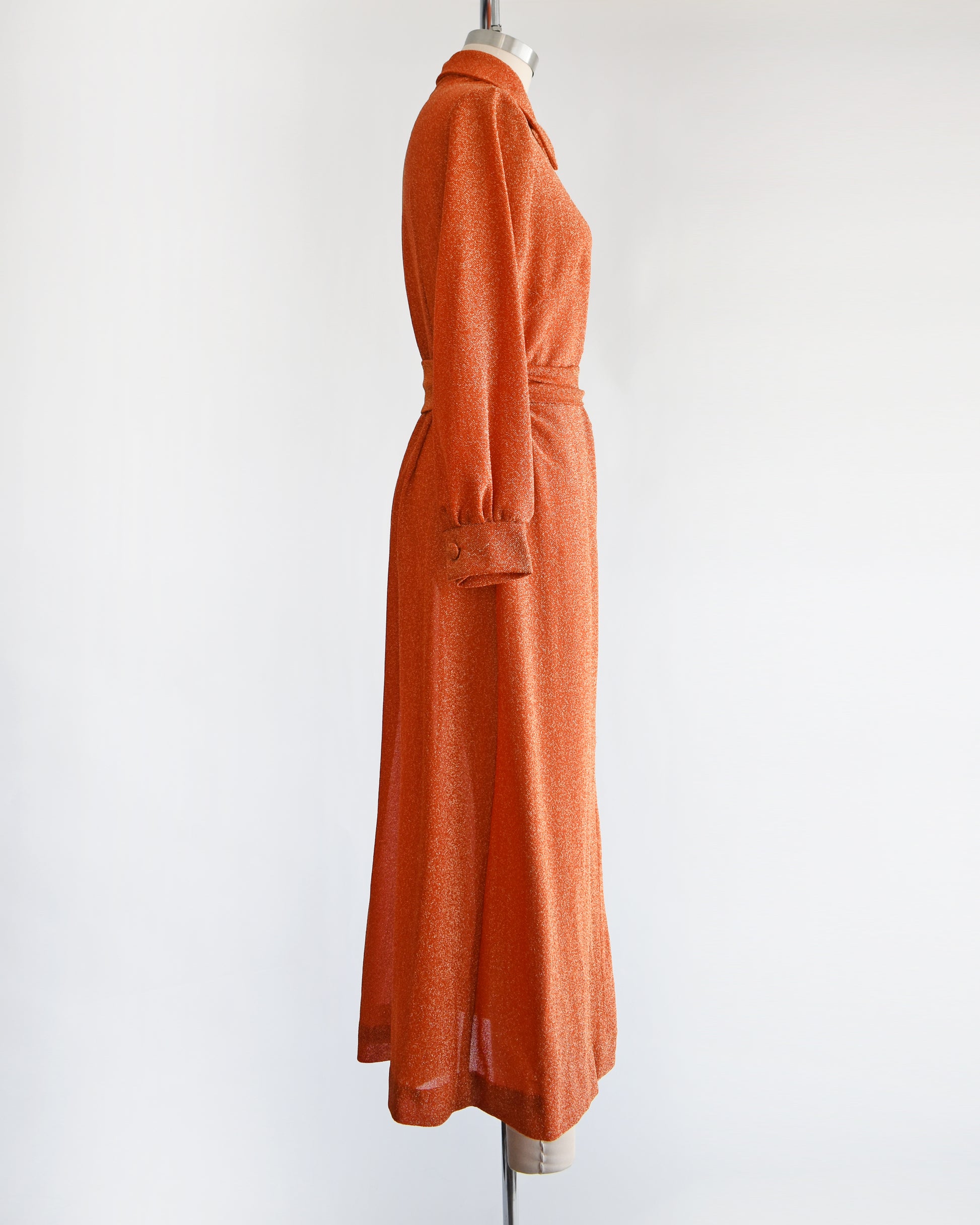 side view of a vintage 1970s orange metallic dress on a mannequin against a white background