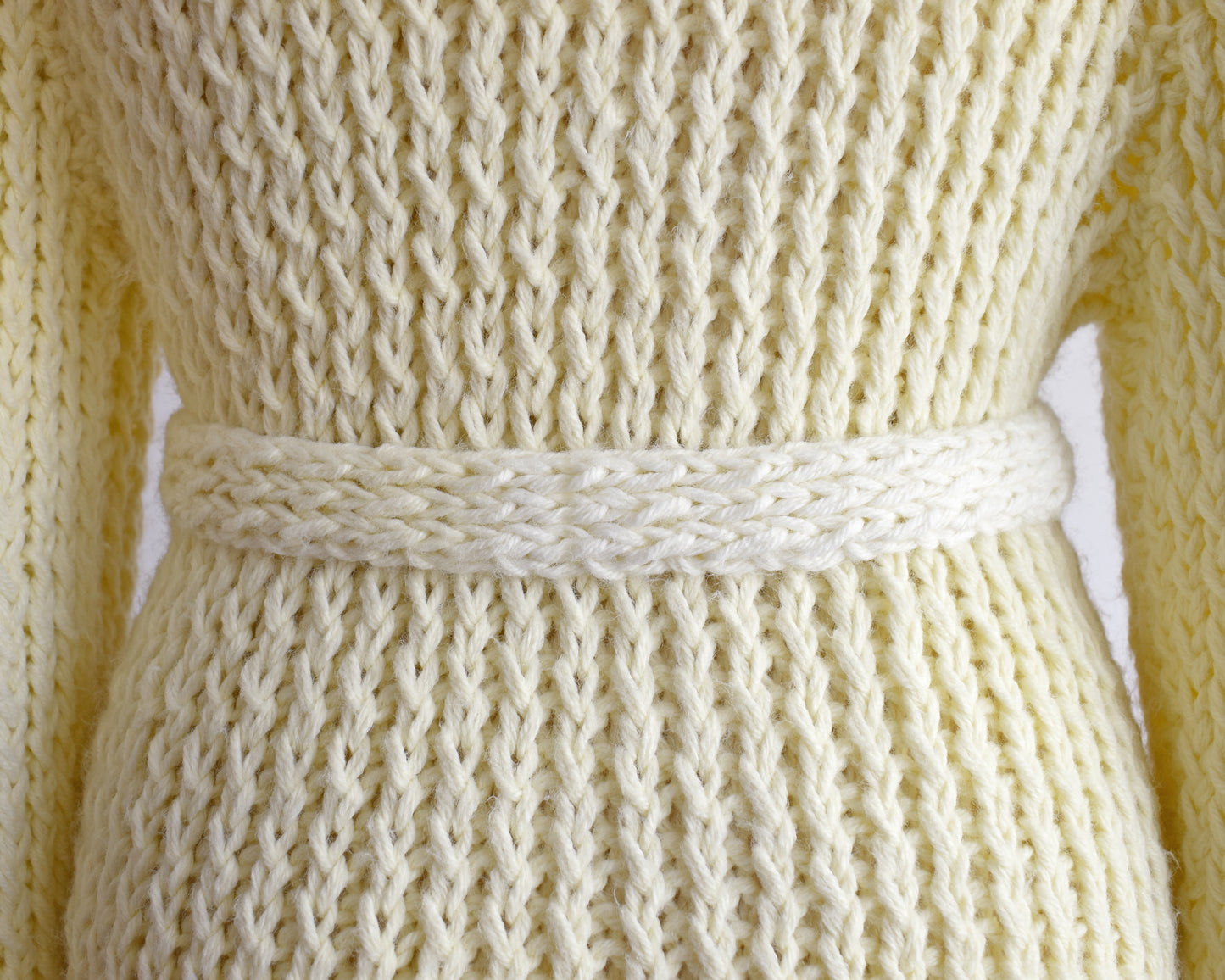 close up of the back of a vintage 1970s cream chunky knit cardigan and it's matching tie belt. The belt is slightly lighter in some spots.