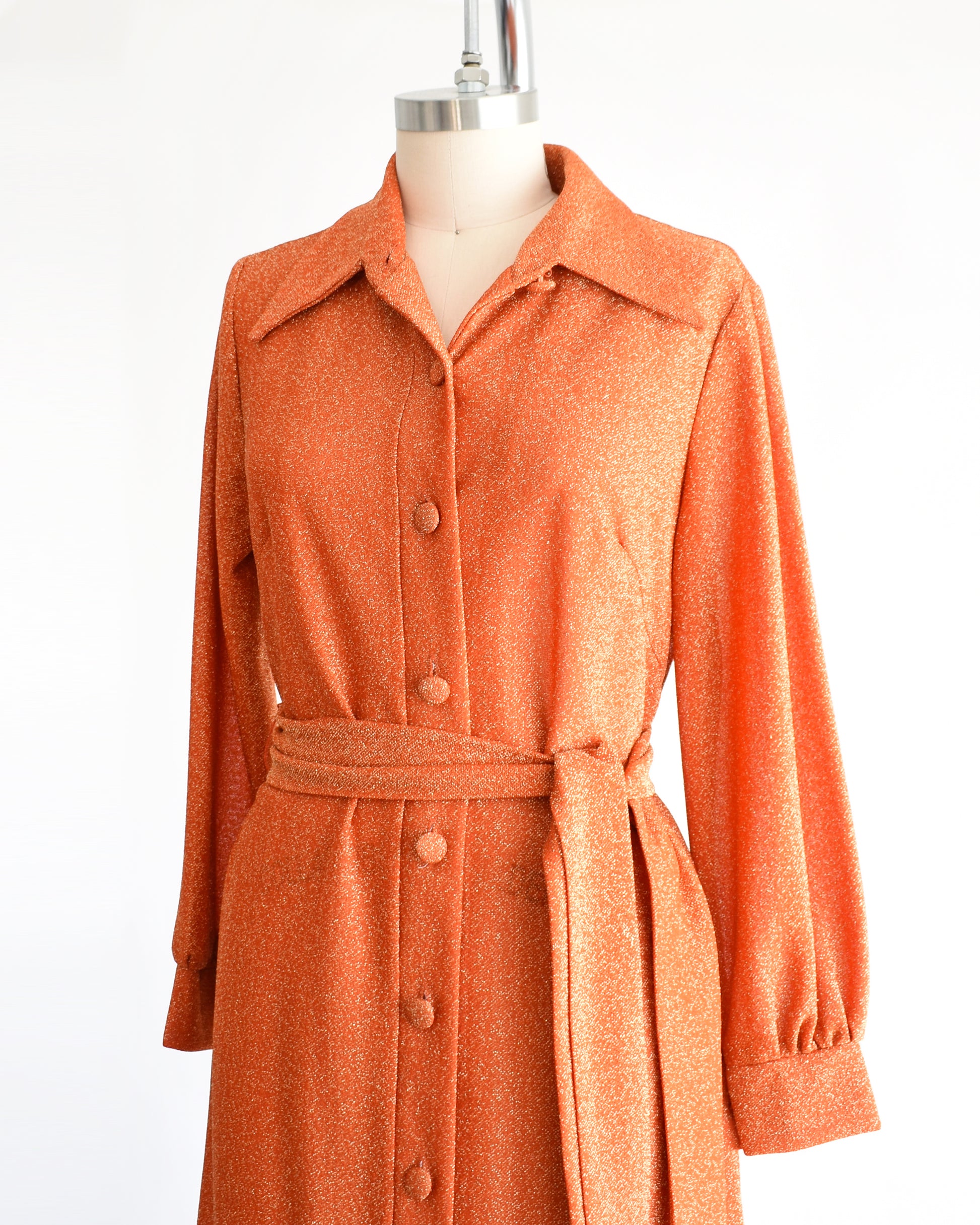 side front view of a vintage 1970s orange metallic dress on a mannequin against a white background
