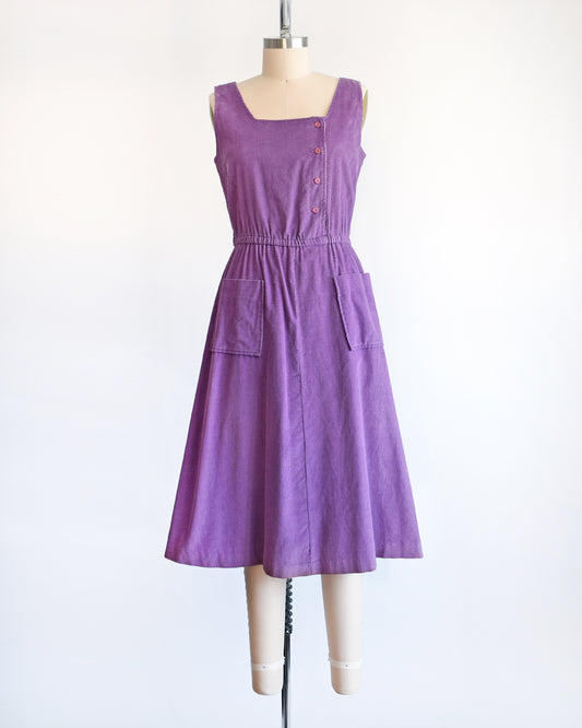 A vintage 1980s purple corduroy pinafore dress on a dress form