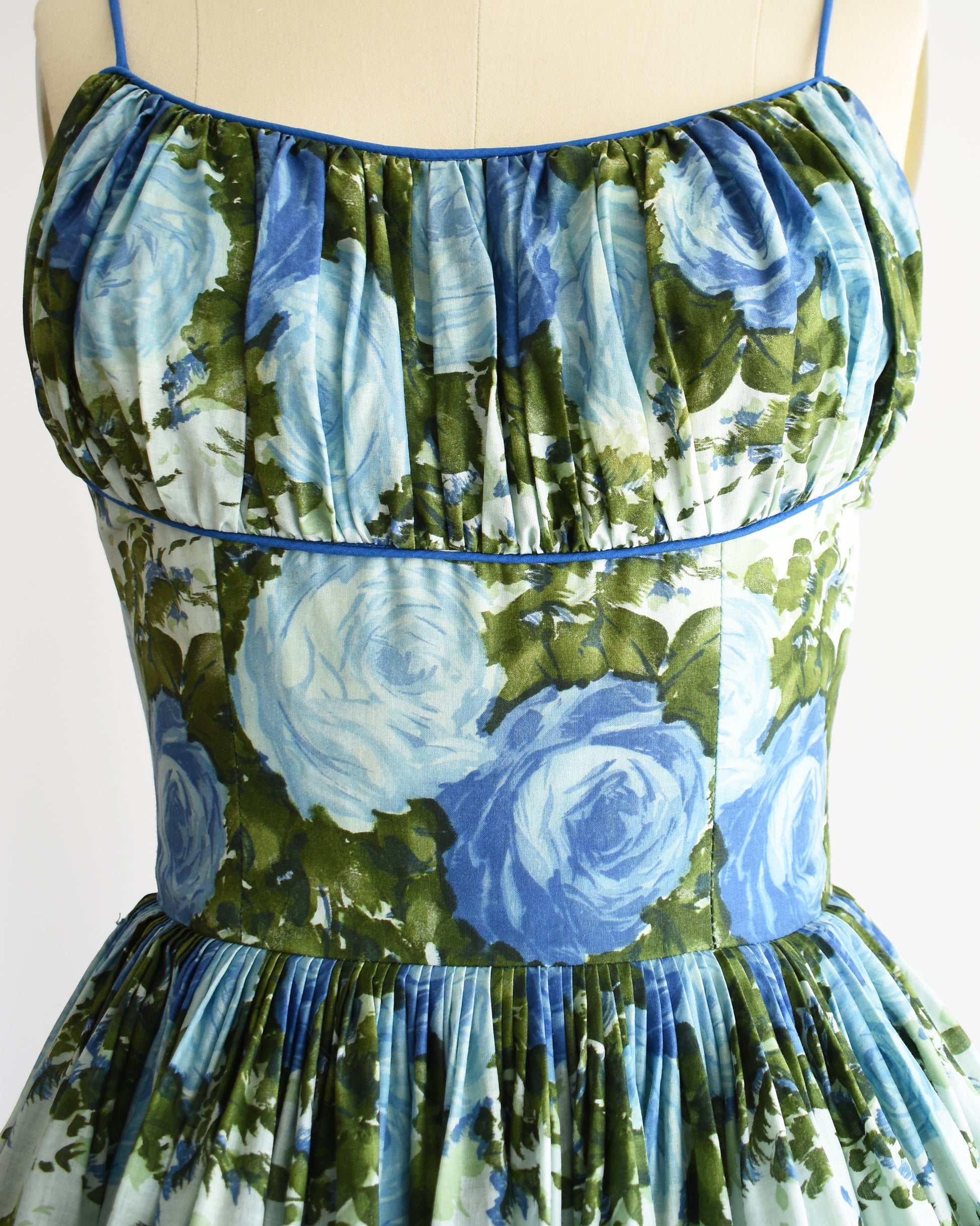 Close up of the bodice of the dress which highlights the gathered shelf bust and blue and green floral print