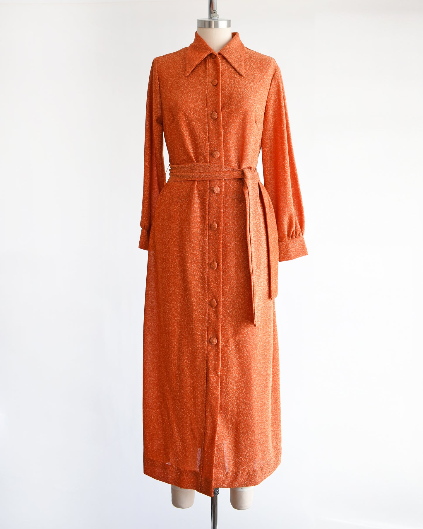 a vintage 1970s orange metallic dress on a mannequin against a white background