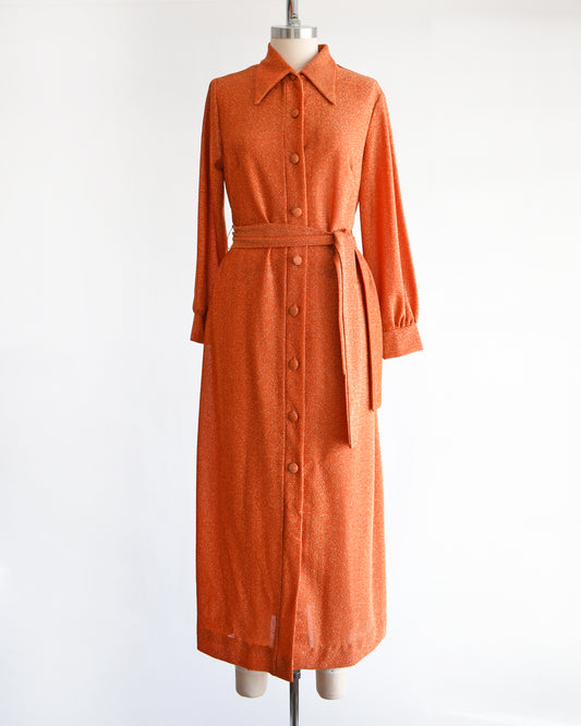 a vintage 1970s orange metallic dress on a mannequin against a white background