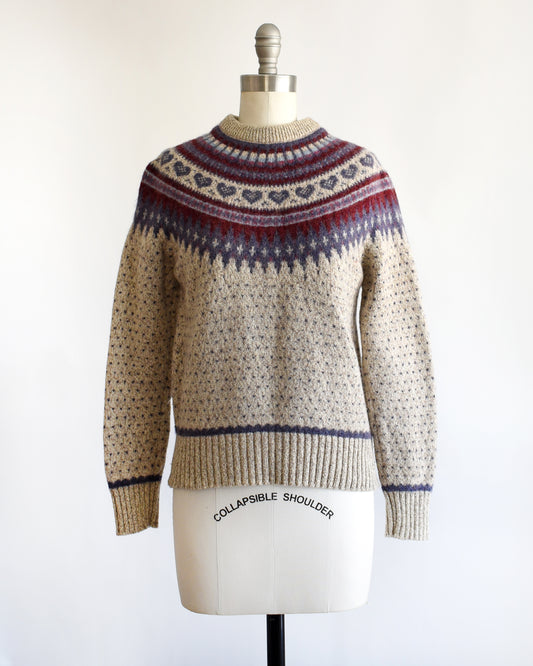 a vintage 1990s knitted fair isle hearts sweater by Eddie Bauer on a mannequin against a white background