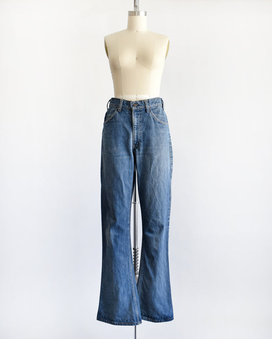 A pair of medium-wash blue denim flare vintage Levi's jeans displayed on a cream-colored dress form mannequin against a plain white background.