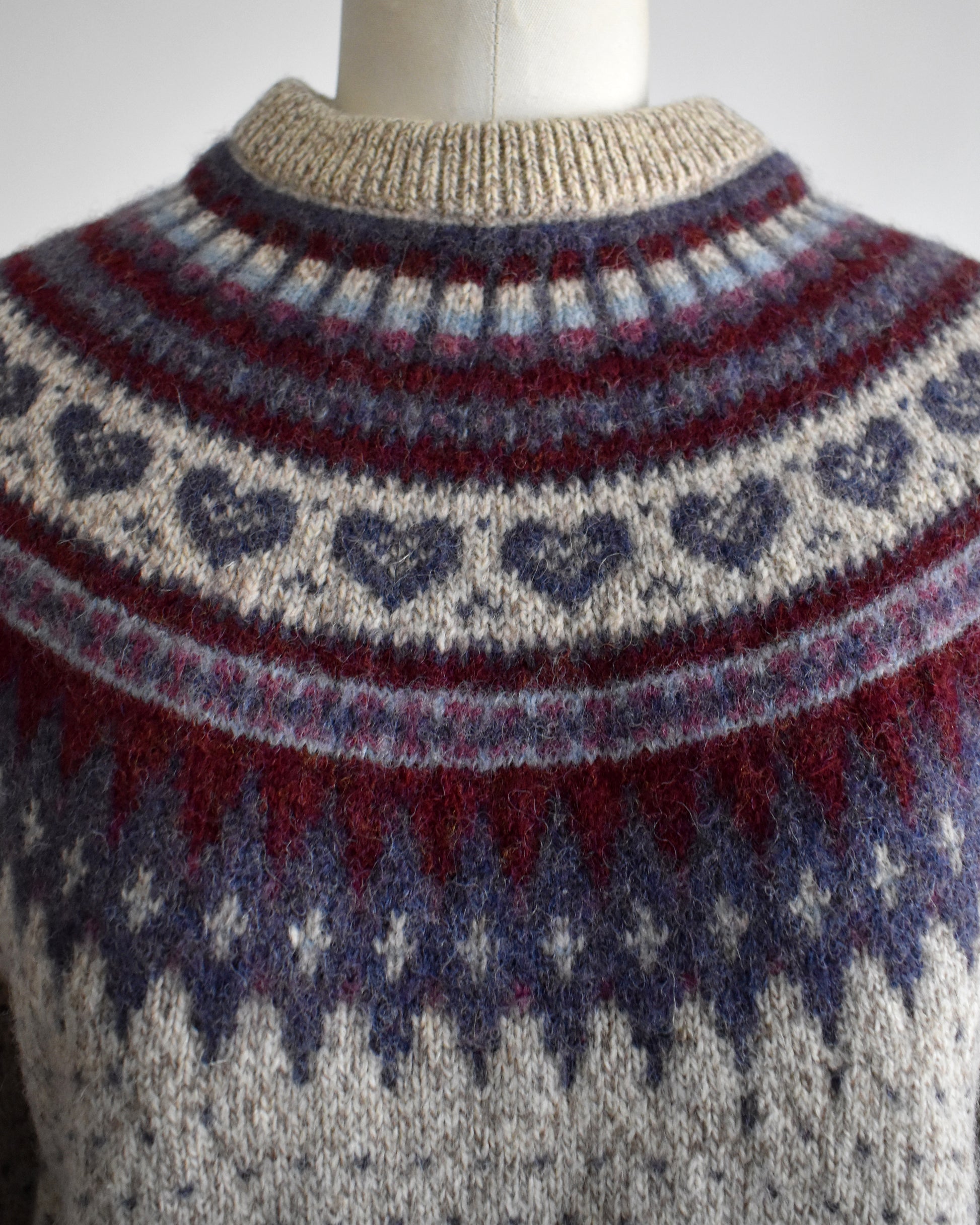 close up of the collar of a vintage 1990s knitted fair isle hearts sweater by Eddie Bauer on a mannequin against a white background
