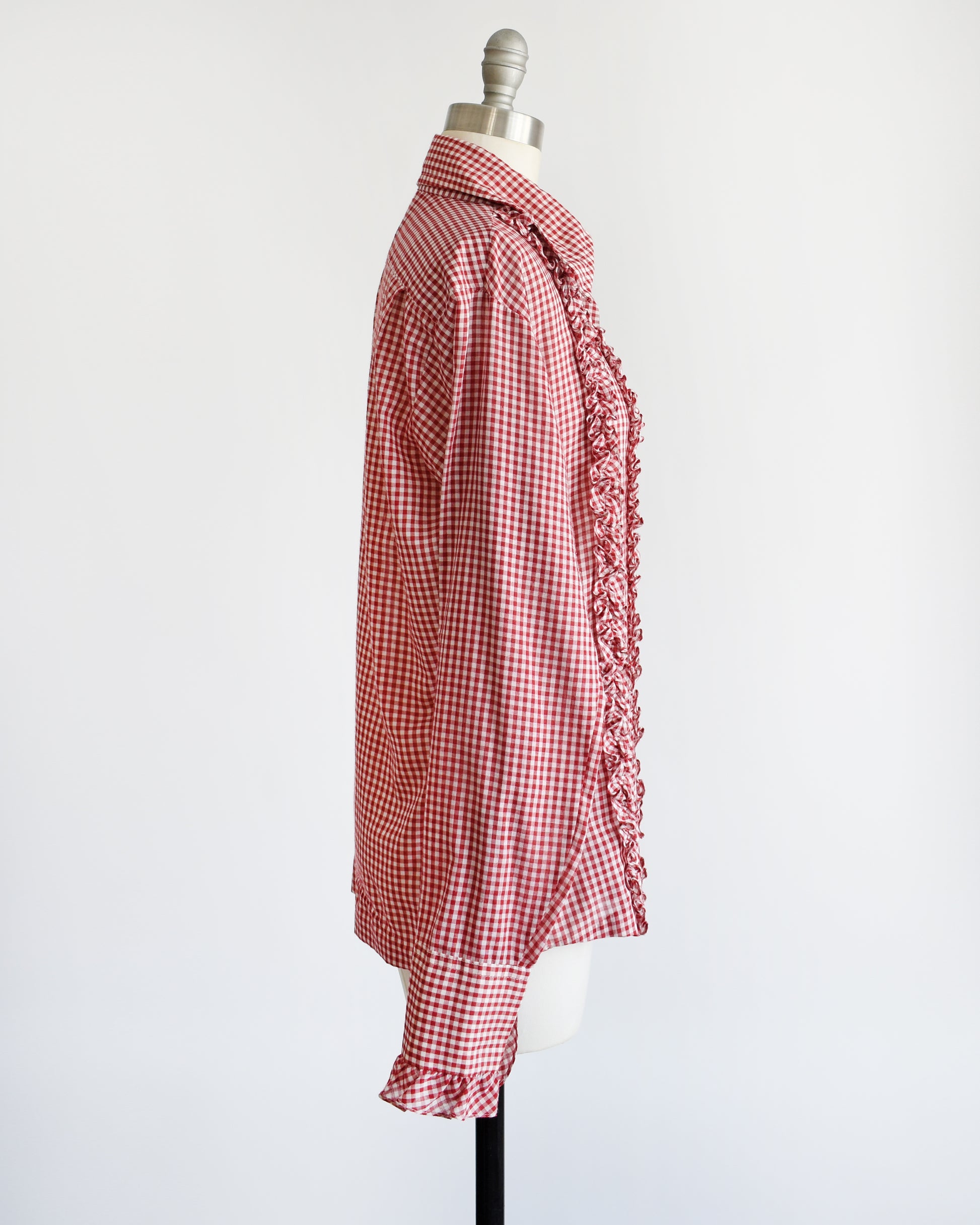 Side view of a vintage 1970s red and white gingham check with plastic buttons down the front and two on the ruffled cuffs