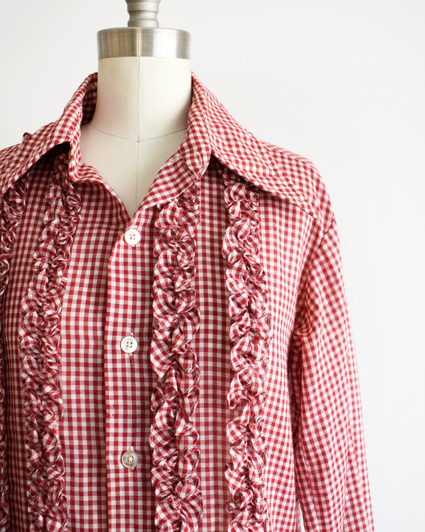 Close up of the red and white check, ruffles on the front, and plastic buttons.