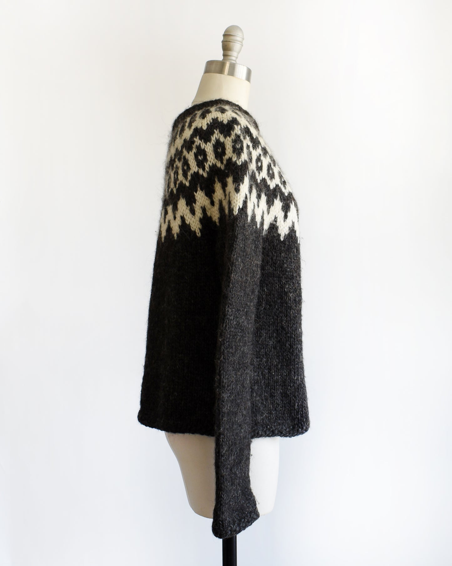 side view of a vintage black and white Fair Isle patterned sweater on a mannequin against a white background