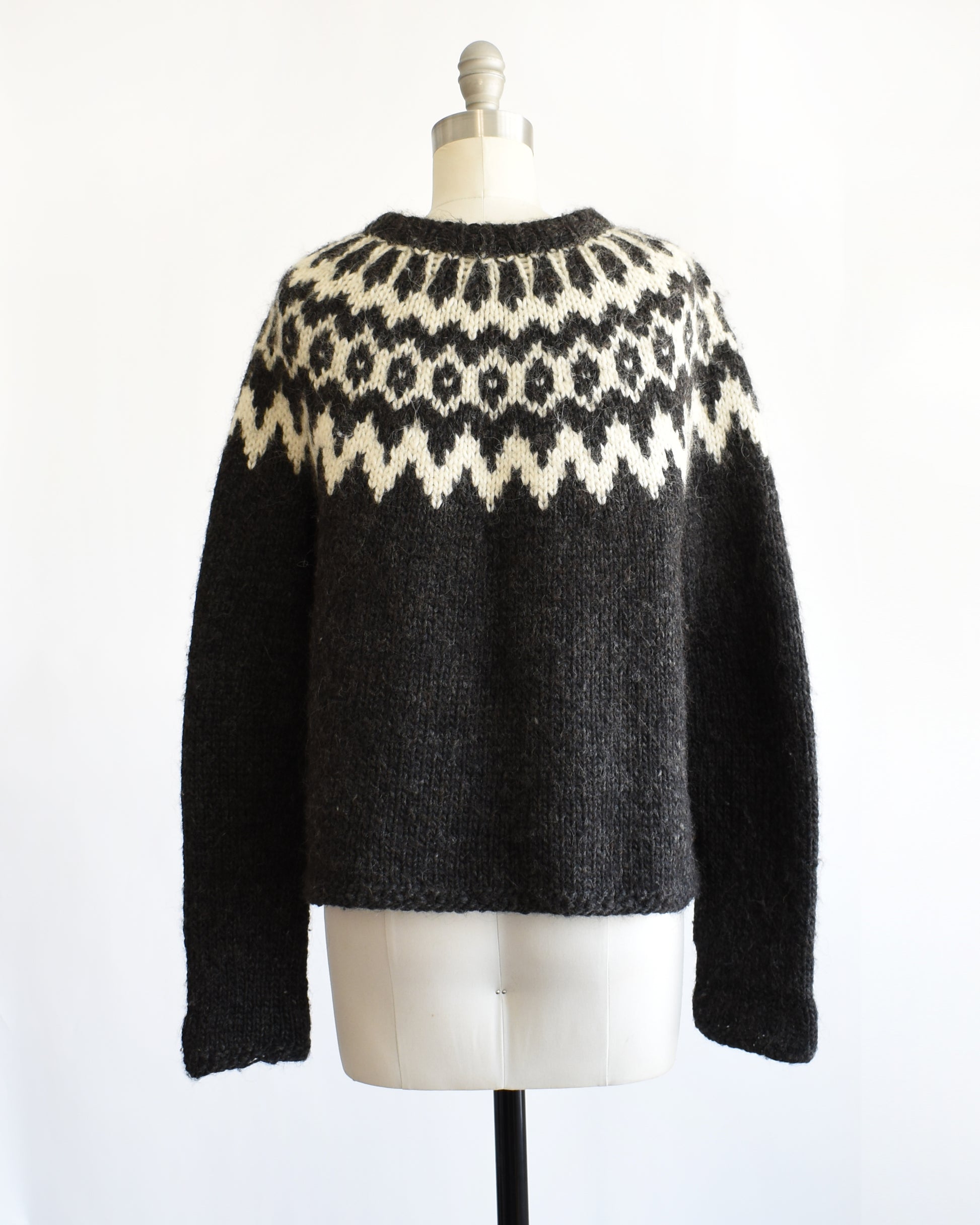 back view of a vintage black and white Fair Isle patterned sweater on a mannequin against a white background