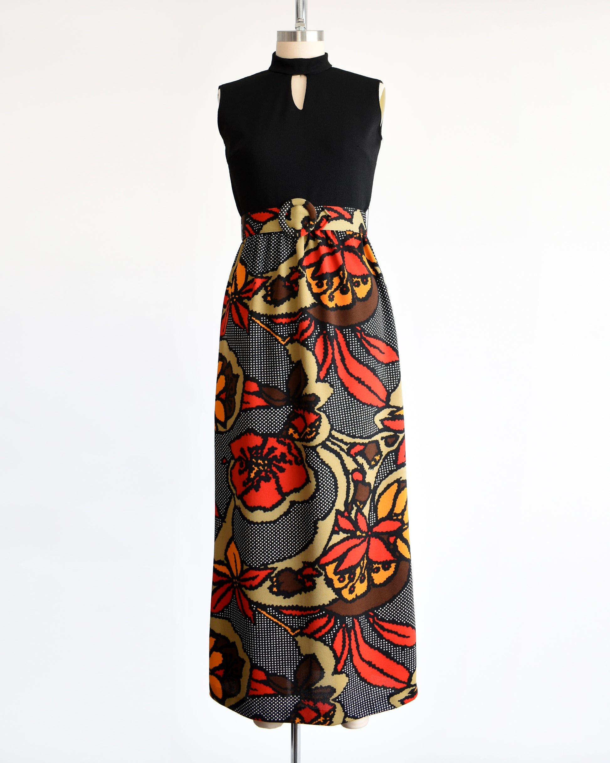 A vintage 1970s maxi dress with a black bodice and a colorful bold floral print skirt with matching belt.