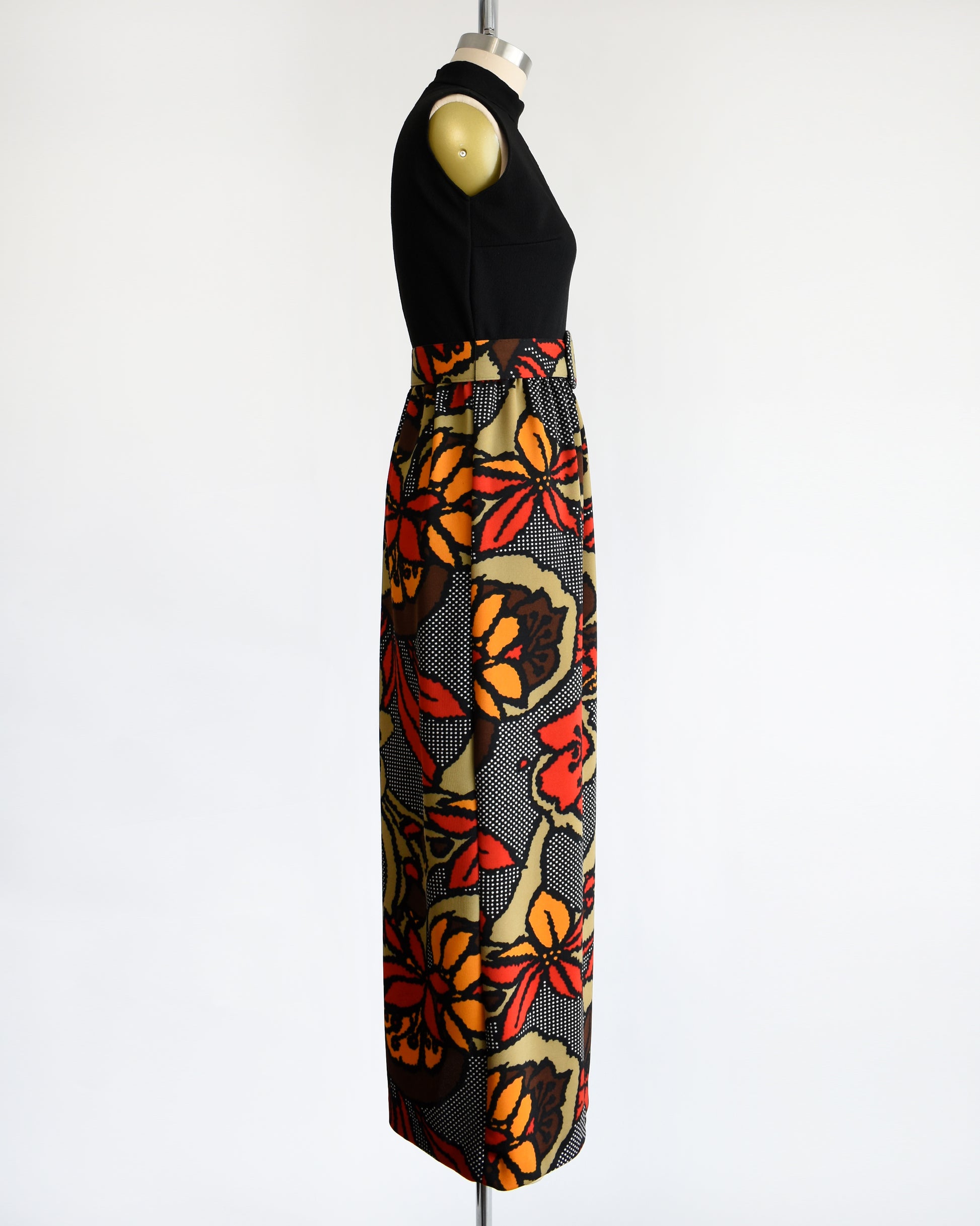 side view of a vintage 1970s maxi dress with a black bodice and a colorful bold floral print skirt with matching belt.