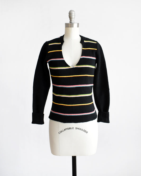 A vintage 1970s sweater that features black knit with horizontal rainbow stripes, a curved v-neckline, and long sleeves that can be cuffed.
