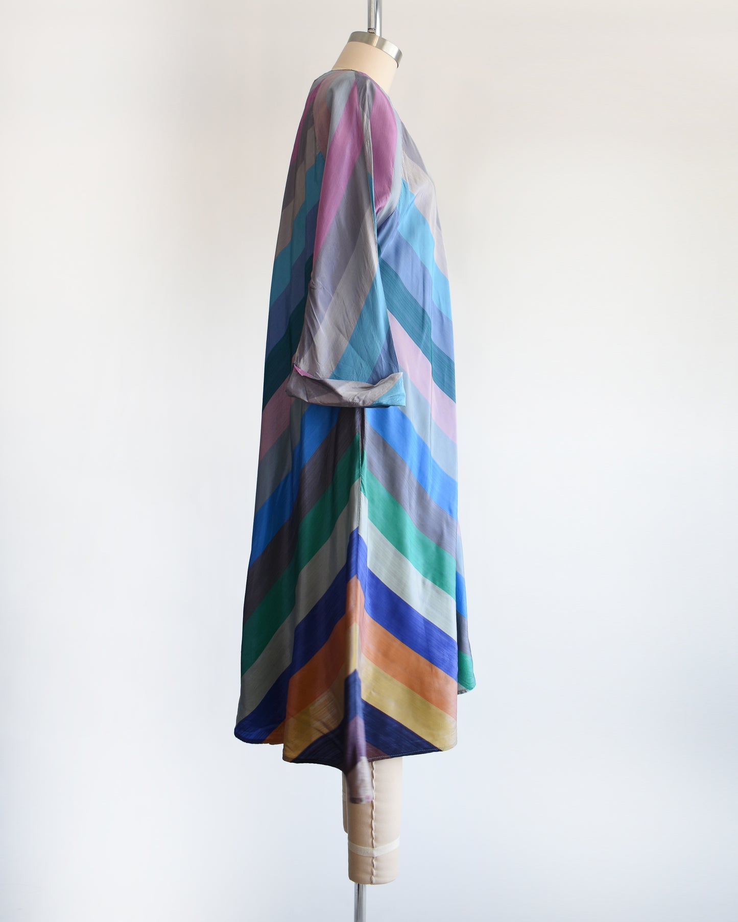 side view of a vintage 1940s multicolored striped dress  robe on a mannequin against a white background