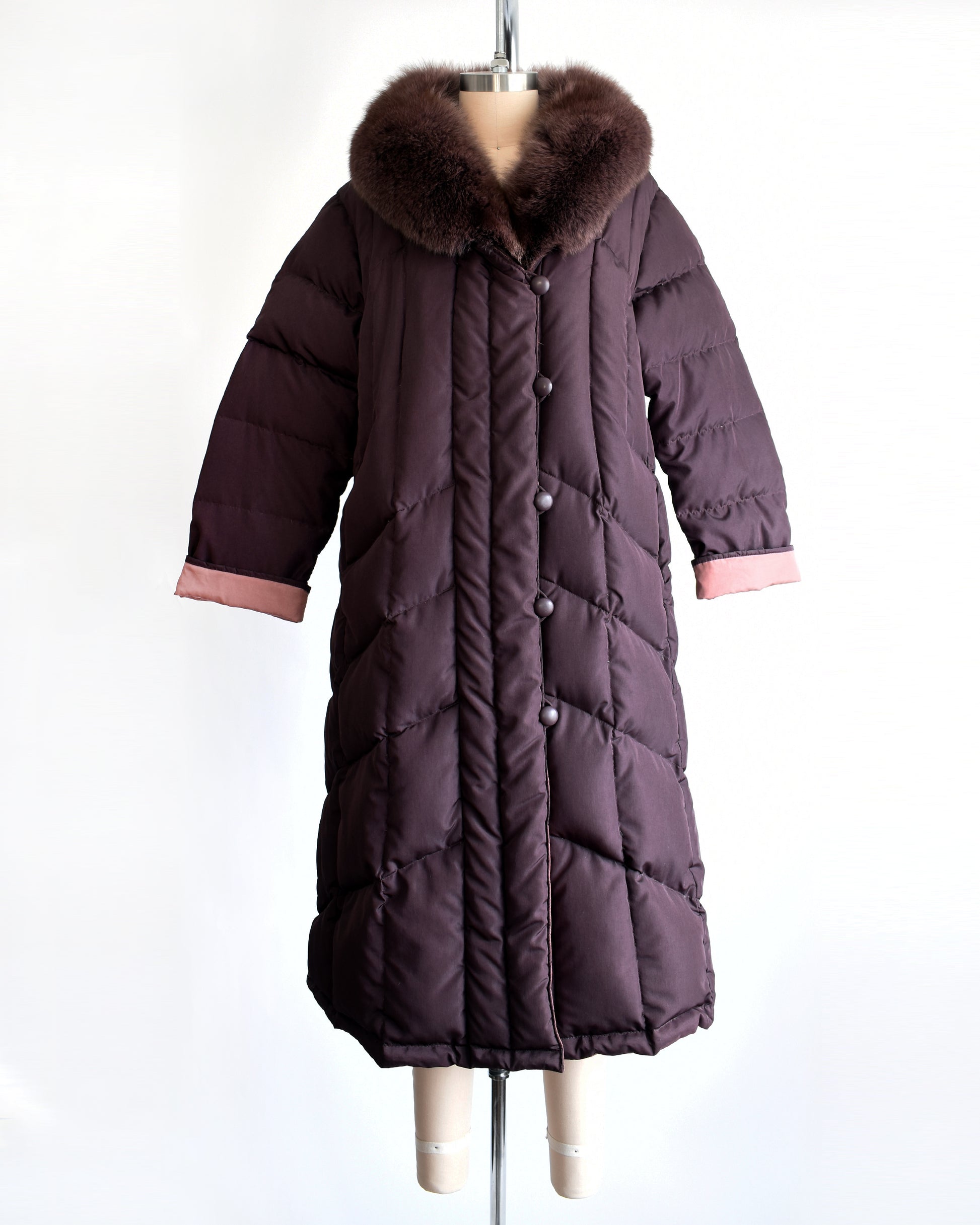 A vintage 1980s dark purple quilted puffer reversible coat with purple faux fur trim