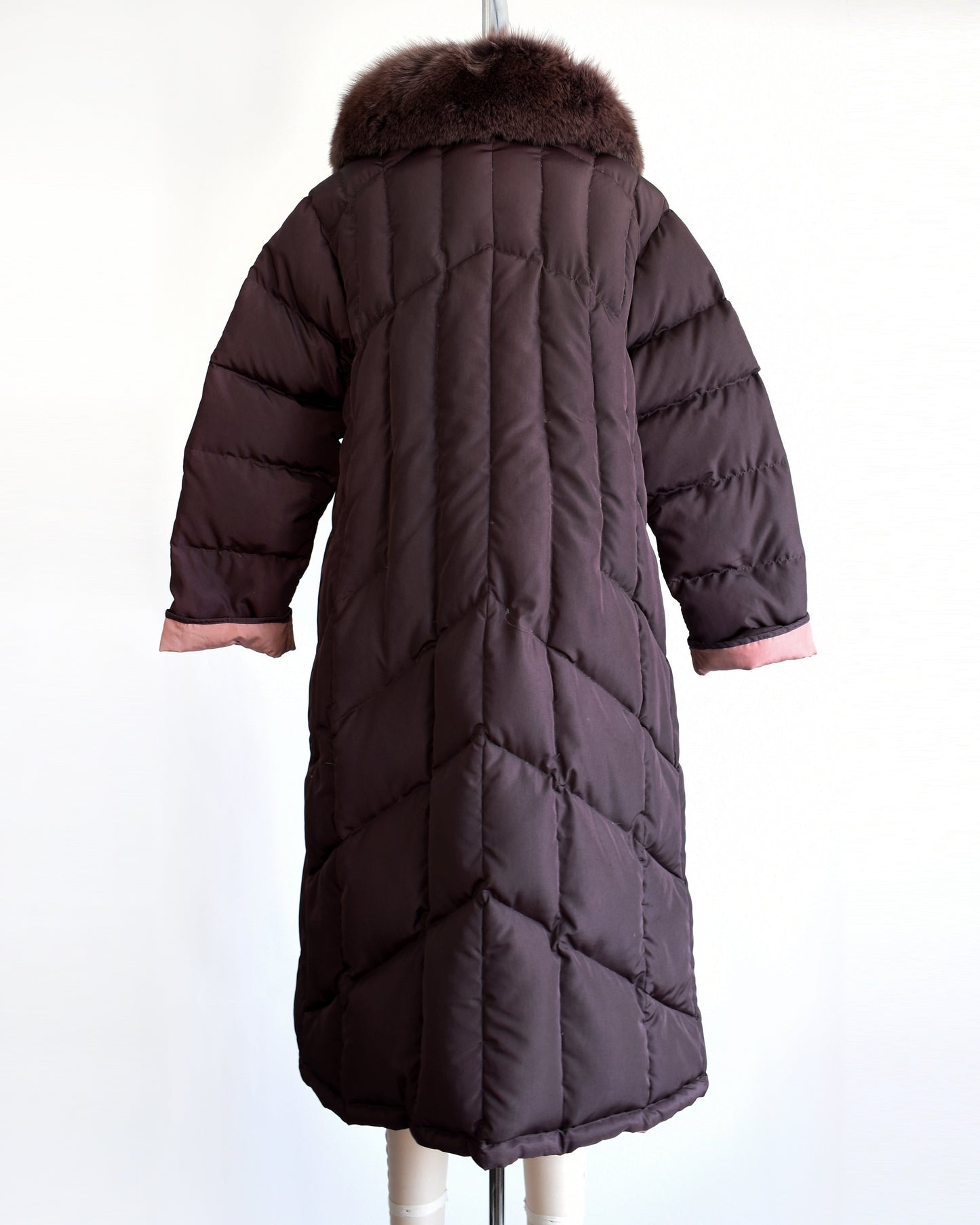 back view of a vintage 1980s dark purple quilted puffer reversible coat with purple faux fur trim