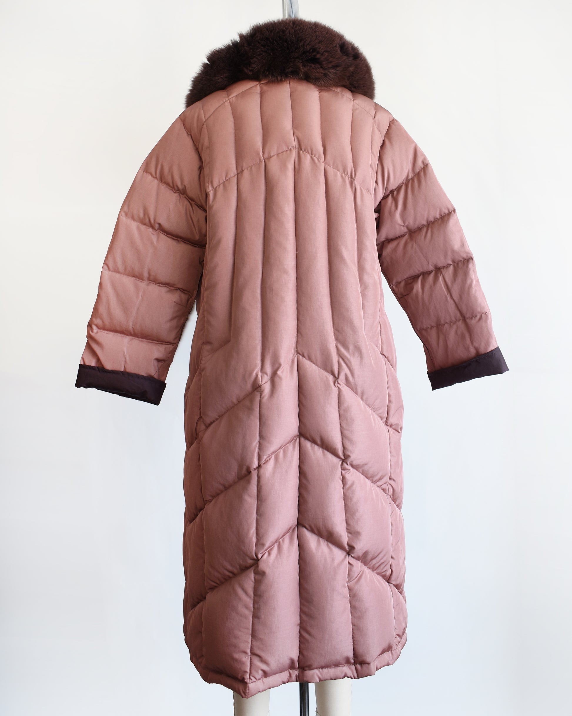 back view of a vintage 1980s quilted puffer reversible coat with purple faux fur trim. this photo shows the mauve side