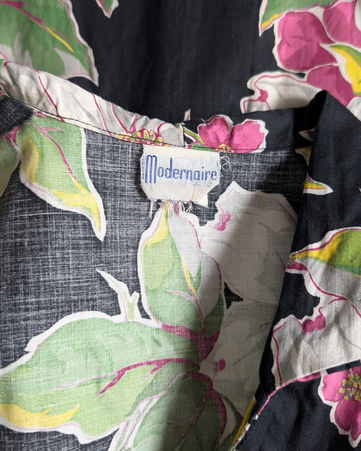 Close-up of a floral-patterned garment with a visible 'Modernaire' brand label. 