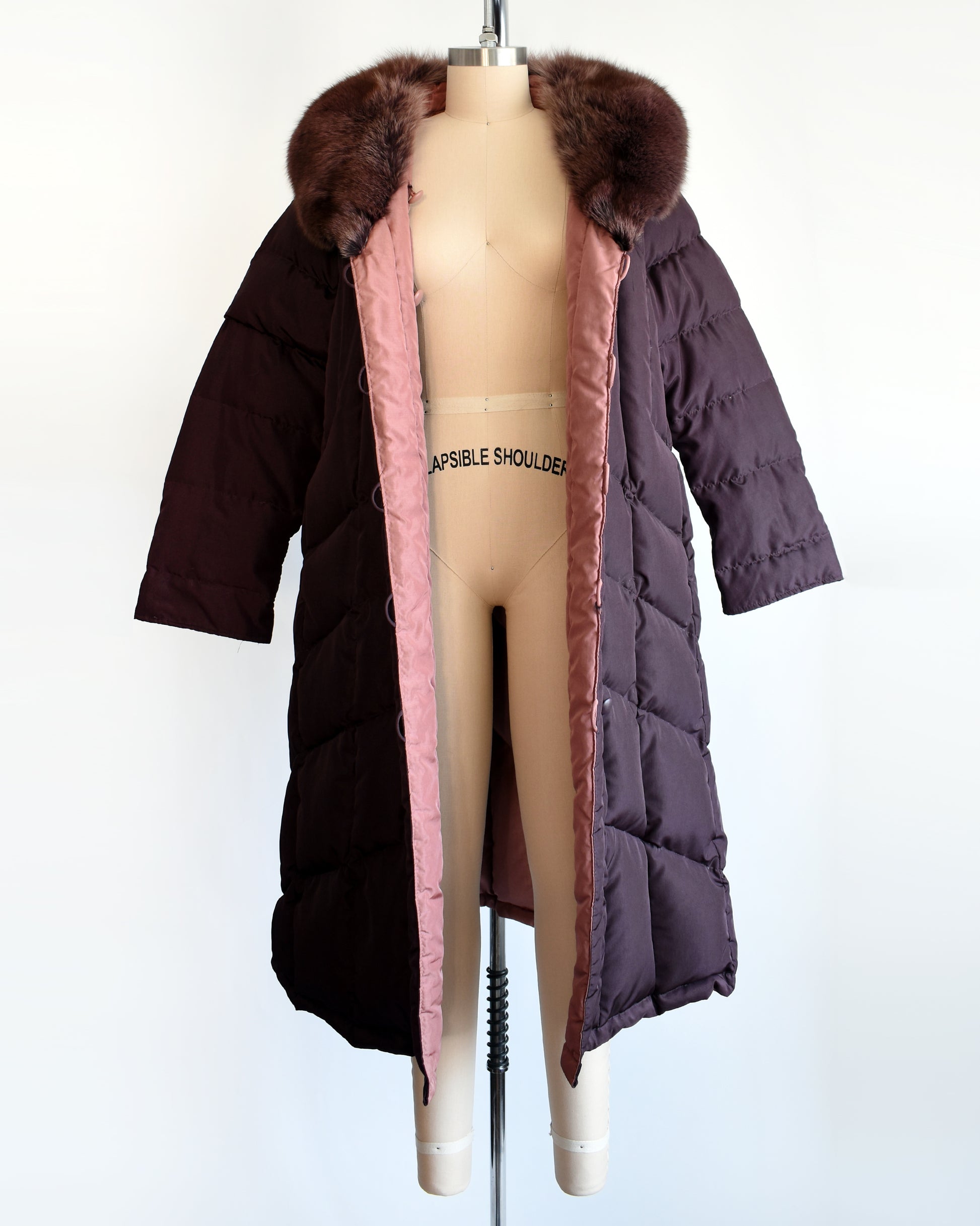 a vintage 1980s dark purple quilted puffer reversible coat with purple faux fur trim. the coat is open showing the mauve inside