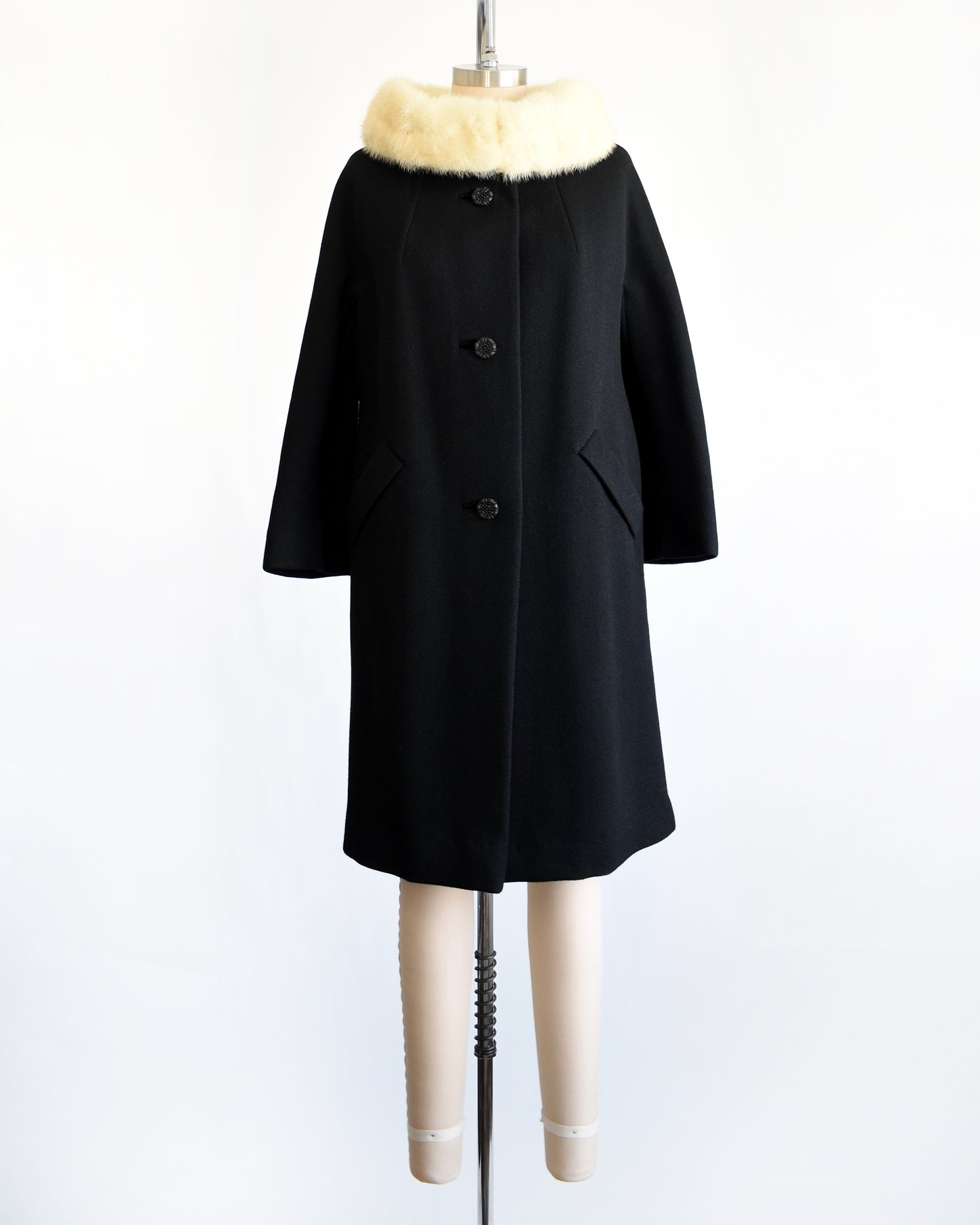 a vintage 1960s Black coat with fur collar on a mannequin against a white background