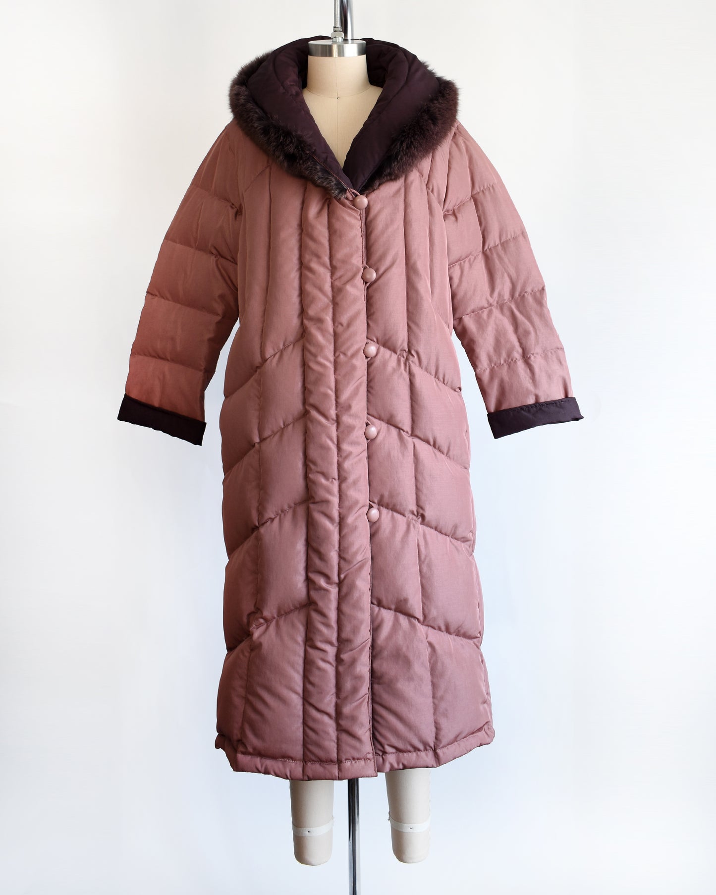 a vintage 1980s quilted puffer reversible coat with purple faux fur trim. this photo shows the mauve side.