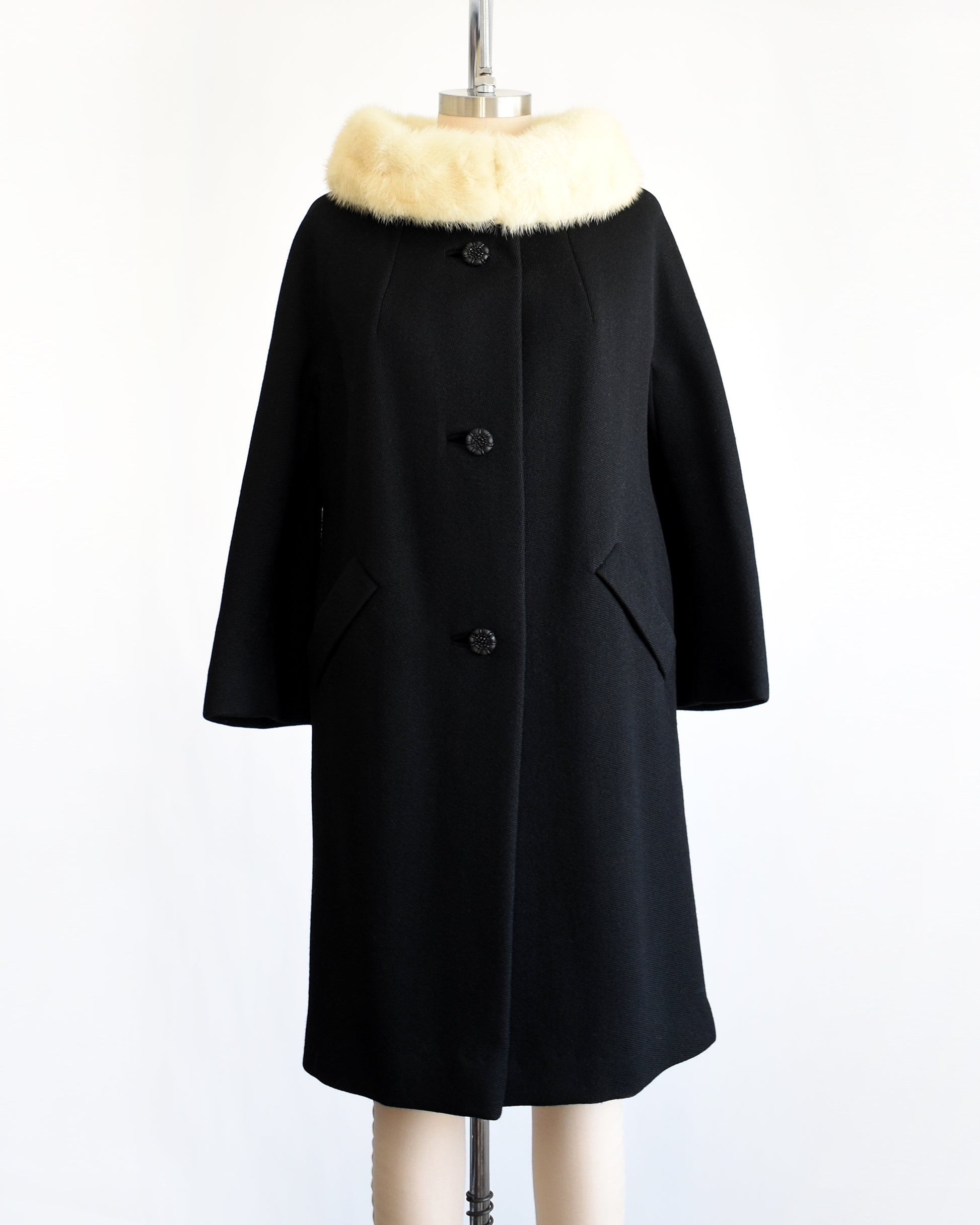 a vintage 1960s Black coat with fur collar on a mannequin against a white background