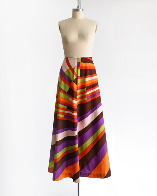 A high-waisted, vintage 1974s Marimekko A-line midi skirt with a bold retro diagonal stripe pattern in orange, purple, brown, green, and cream, displayed on a mannequin against a white background.