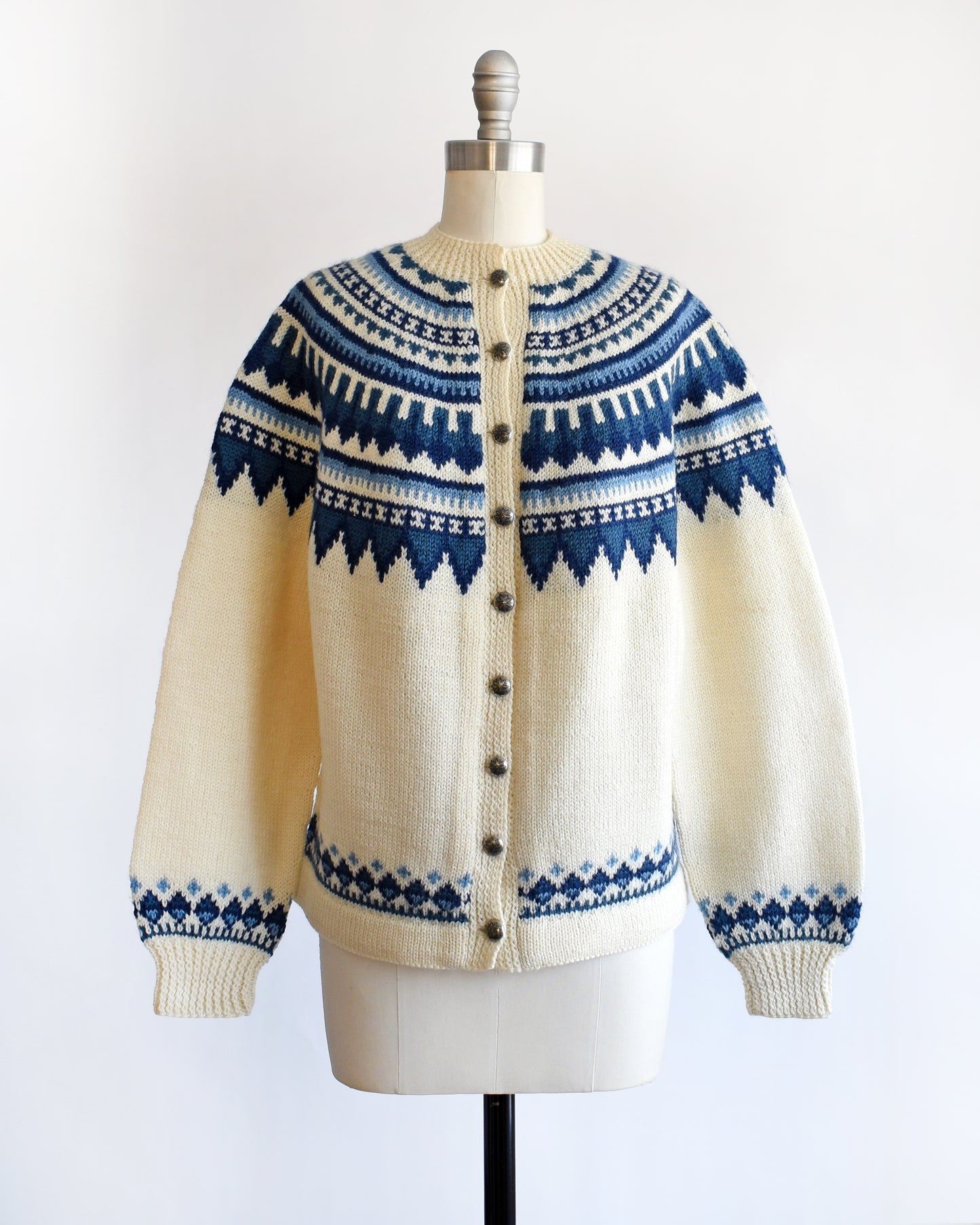 a vintage 1970s Cream-colored Fair Isle sweater with blue and white pattern on a mannequin against a white background