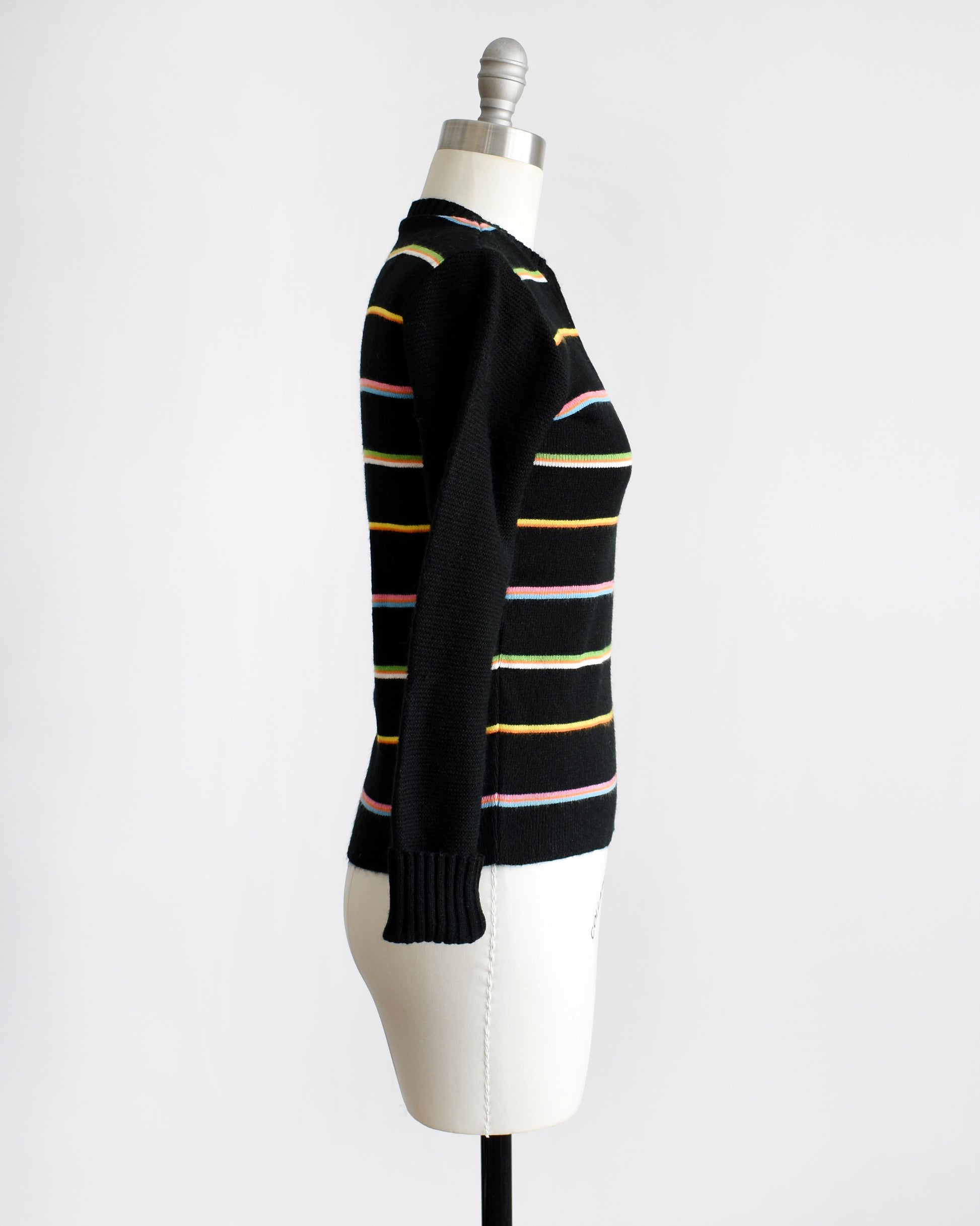 Side view of a vintage 1970s sweater that features black knit with horizontal rainbow stripes