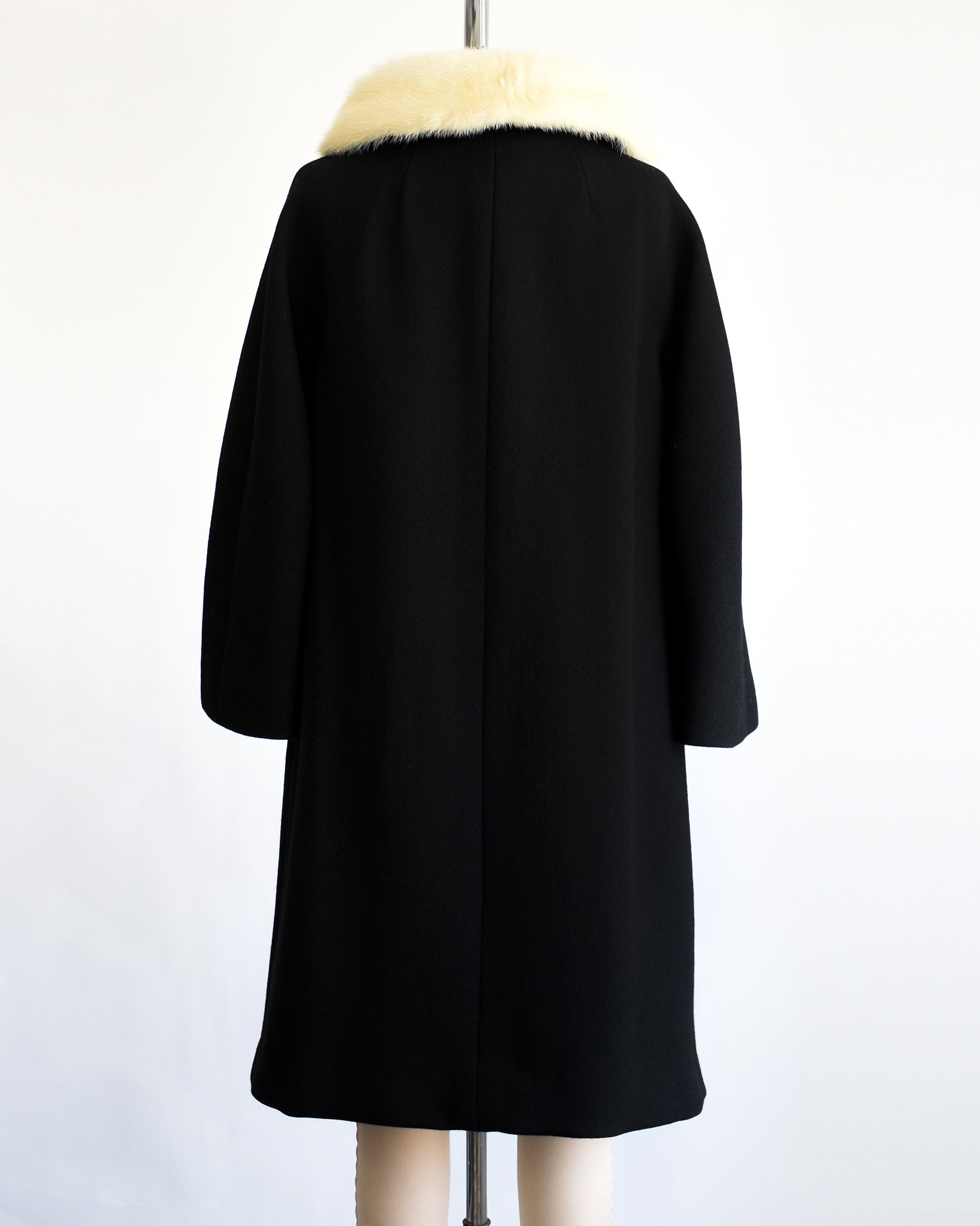 back view of a vintage 1960s Black coat with fur collar on a mannequin against a white background