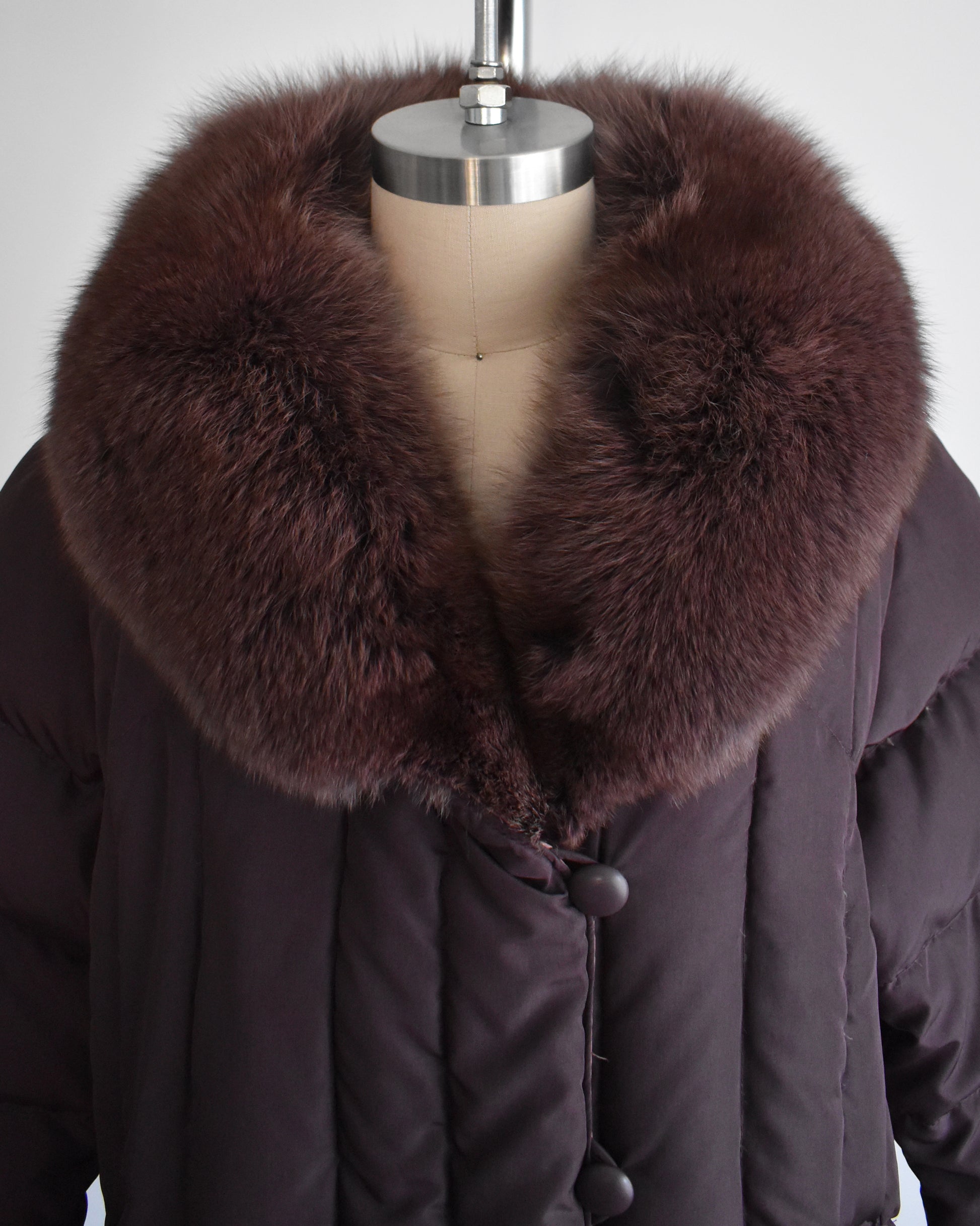 close up of a vintage 1980s dark purple quilted puffer reversible coat with purple faux fur trim