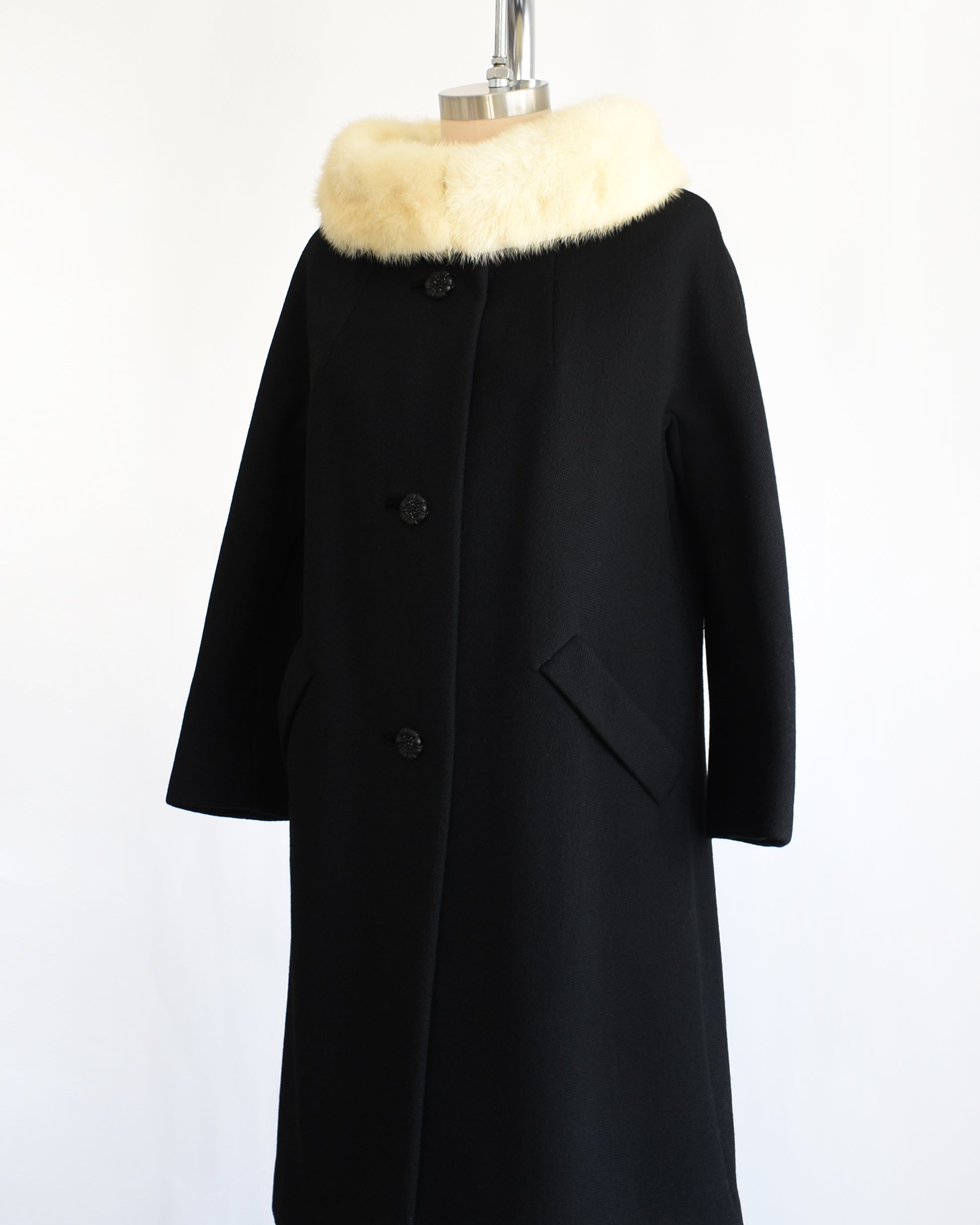 side front view of a vintage 1960s Black coat with fur collar on a mannequin against a white background