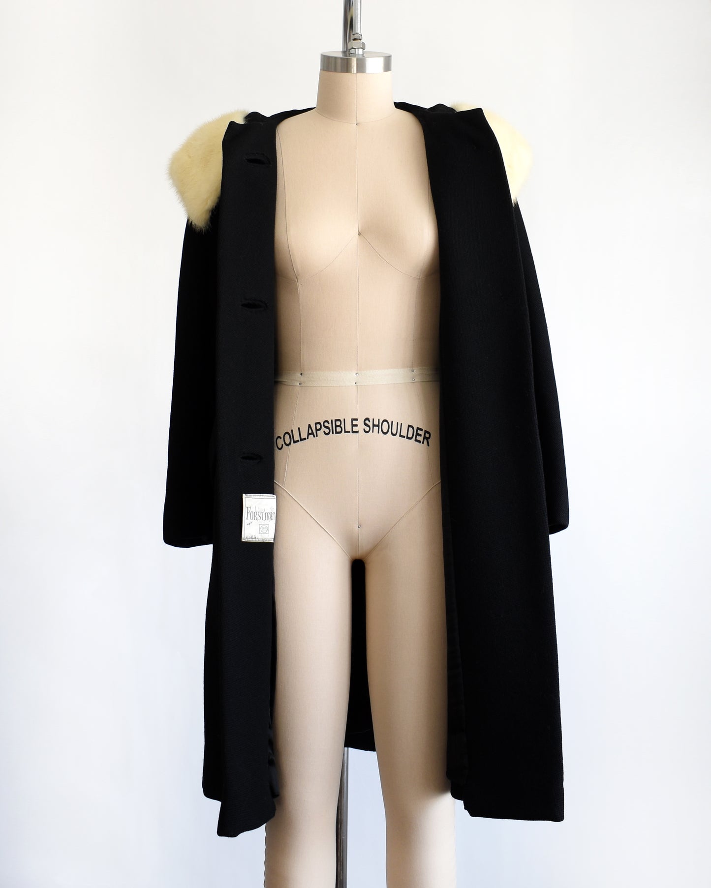 a vintage 1960s Black coat with fur collar on a mannequin against a white background. the coat is opened in this photo