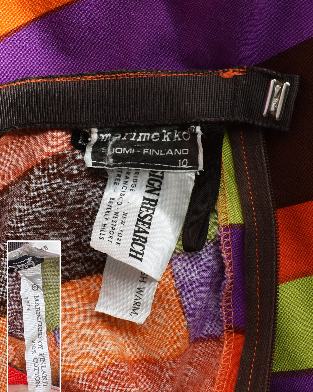 Close-up of a garment's inner waist area showing a brown grosgrain ribbon, a Marimekko label, and a white care tag, with a small inset image showing the another tag.