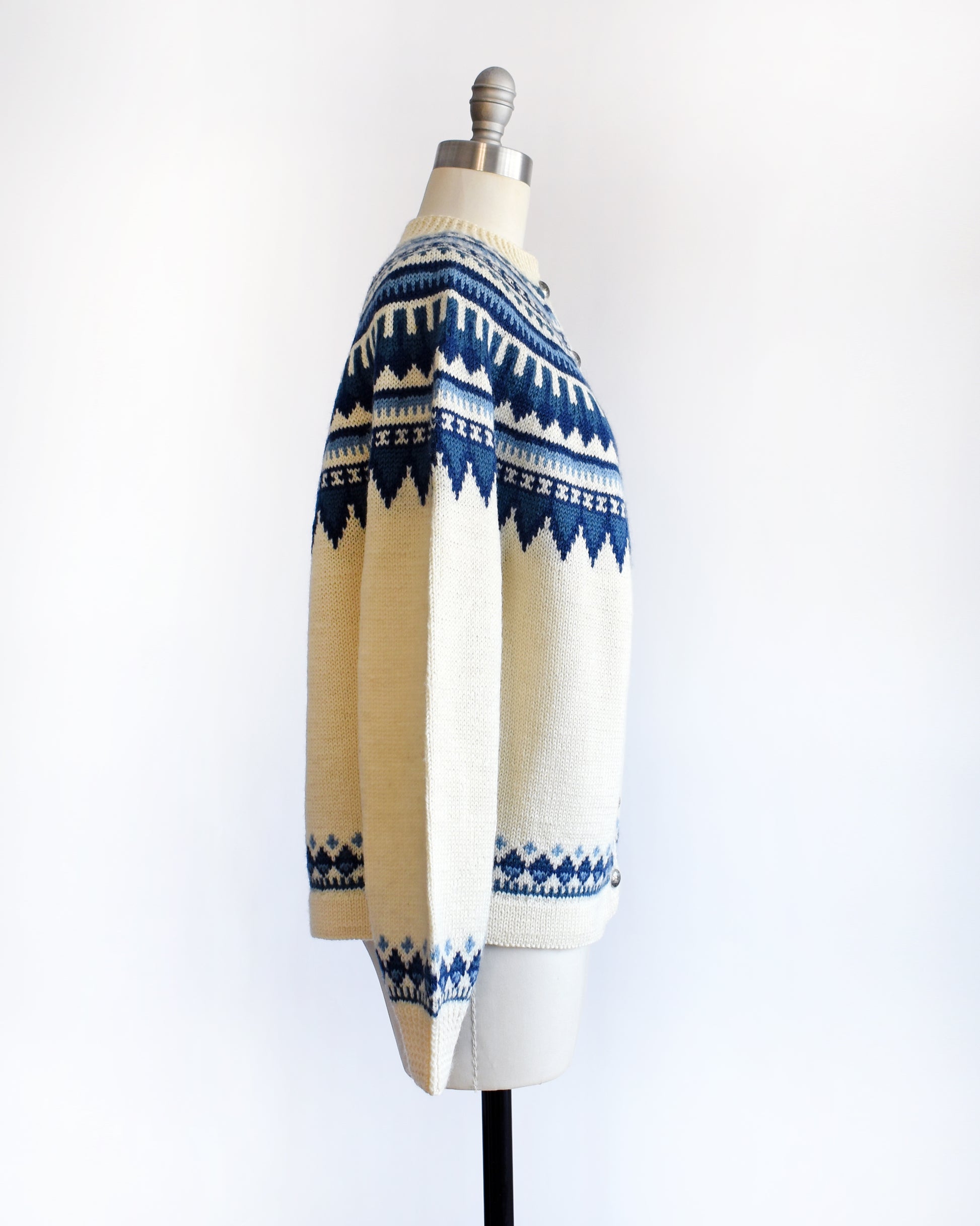 side view of a vintage 1970s Cream-colored Fair Isle sweater with blue and white pattern on a mannequin against a white background
