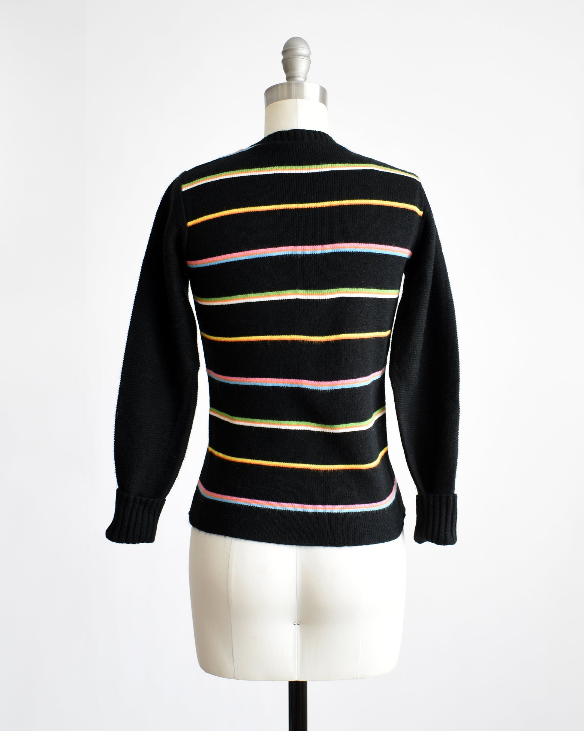 Back view of a vintage 1970s sweater that features black knit with horizontal rainbow stripes
