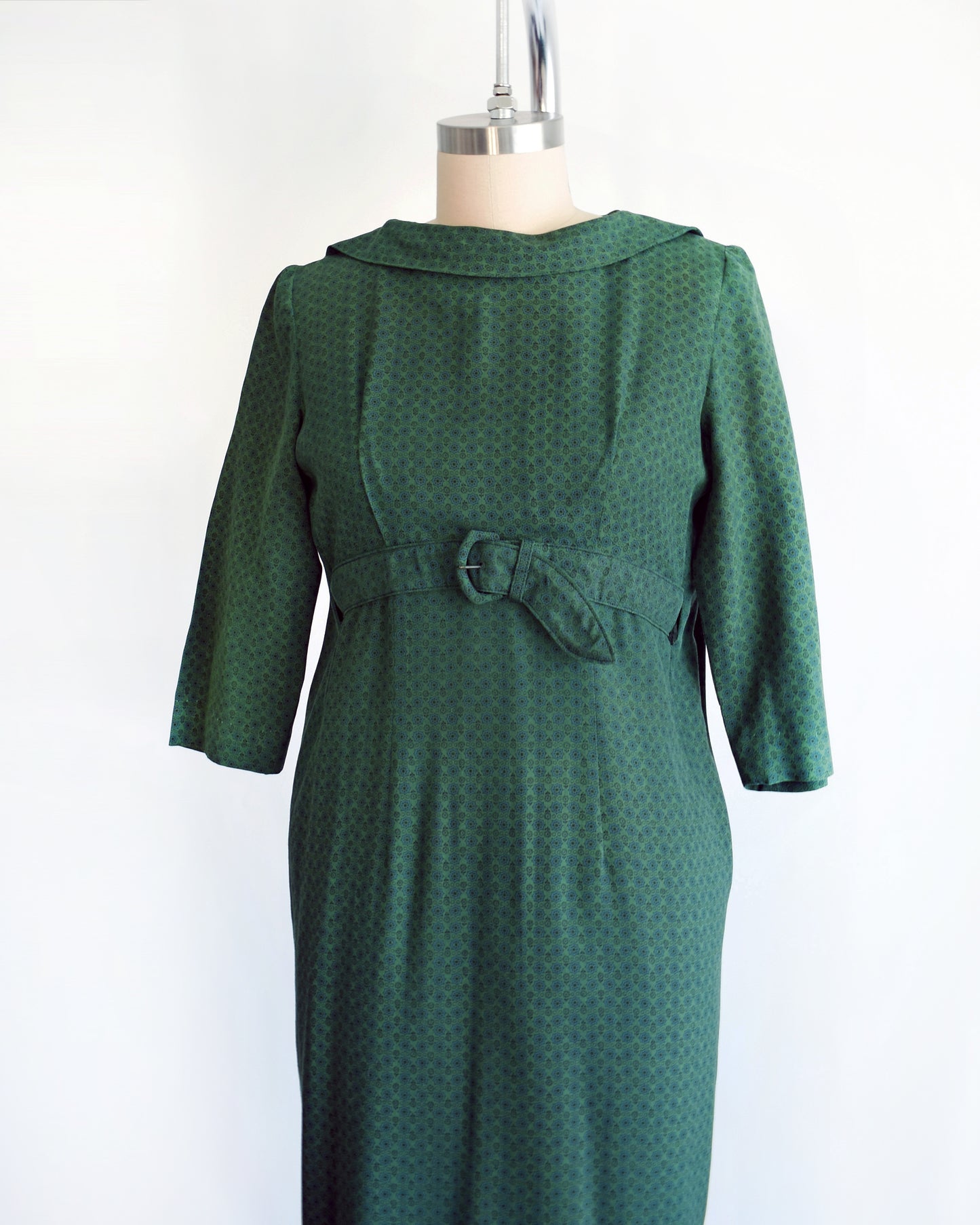 side front view of a vintage late 1950s early 1960s green floral wiggle dress with empire waist belt