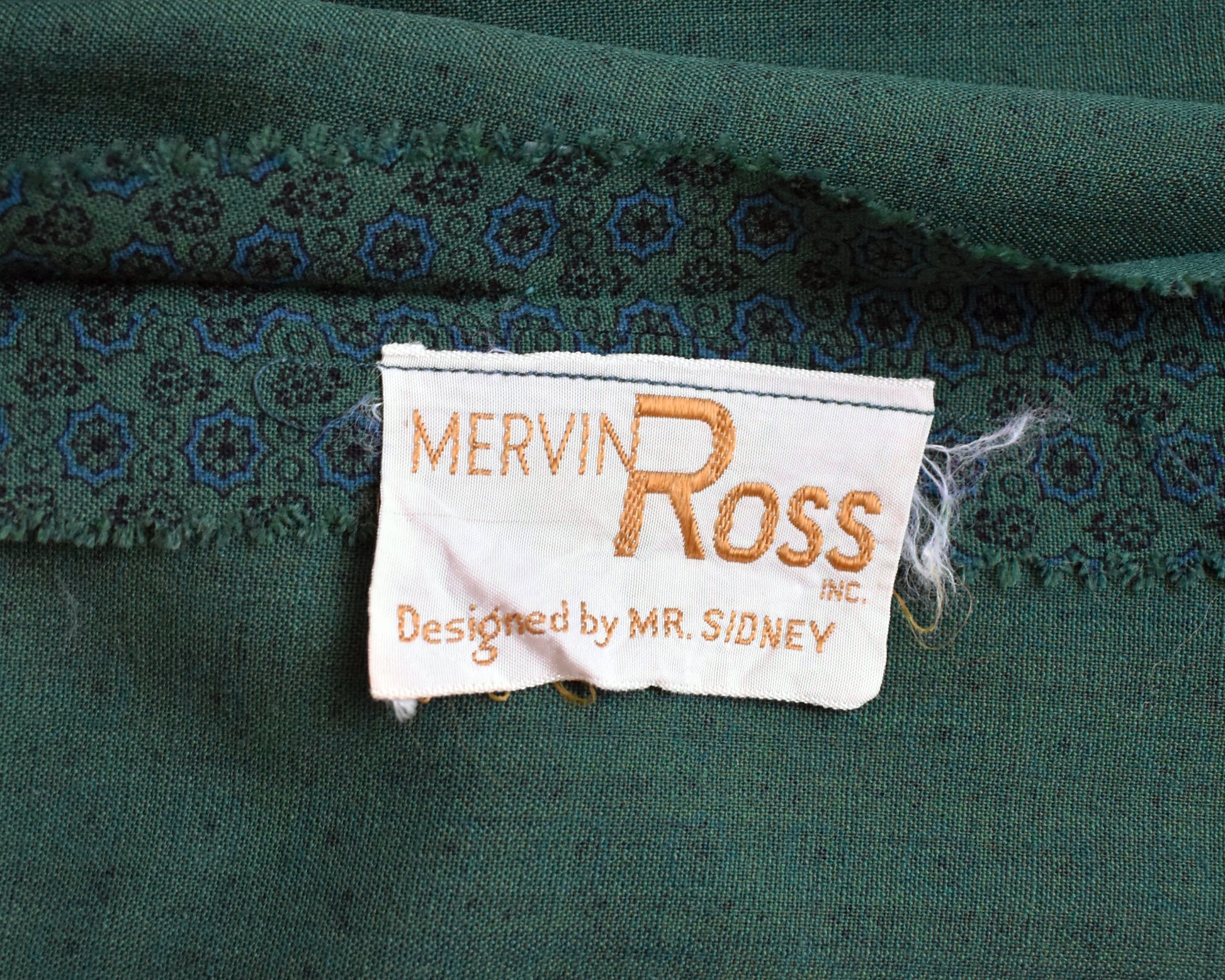 close up of the tag which says Mervin Ross INC. Designed by Mr. Sidney