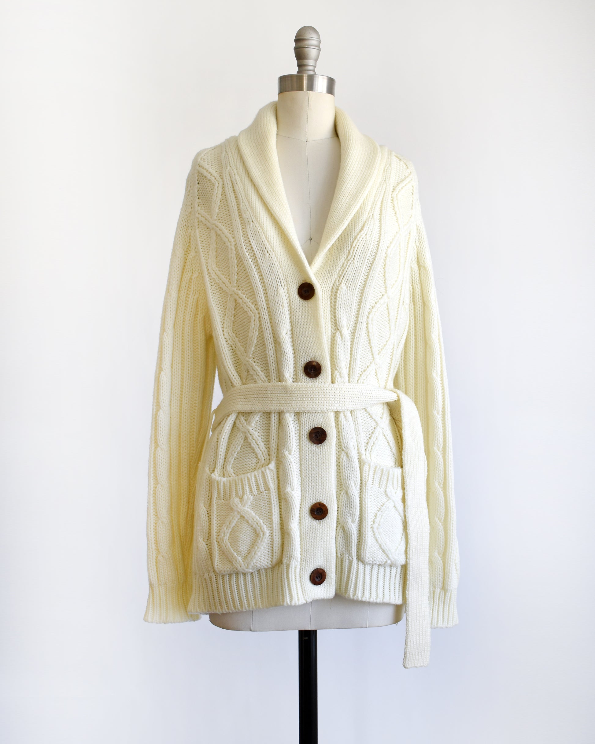 a vintage 1980s cream cable knit cardigan with faux wood buttons and matching tie belt