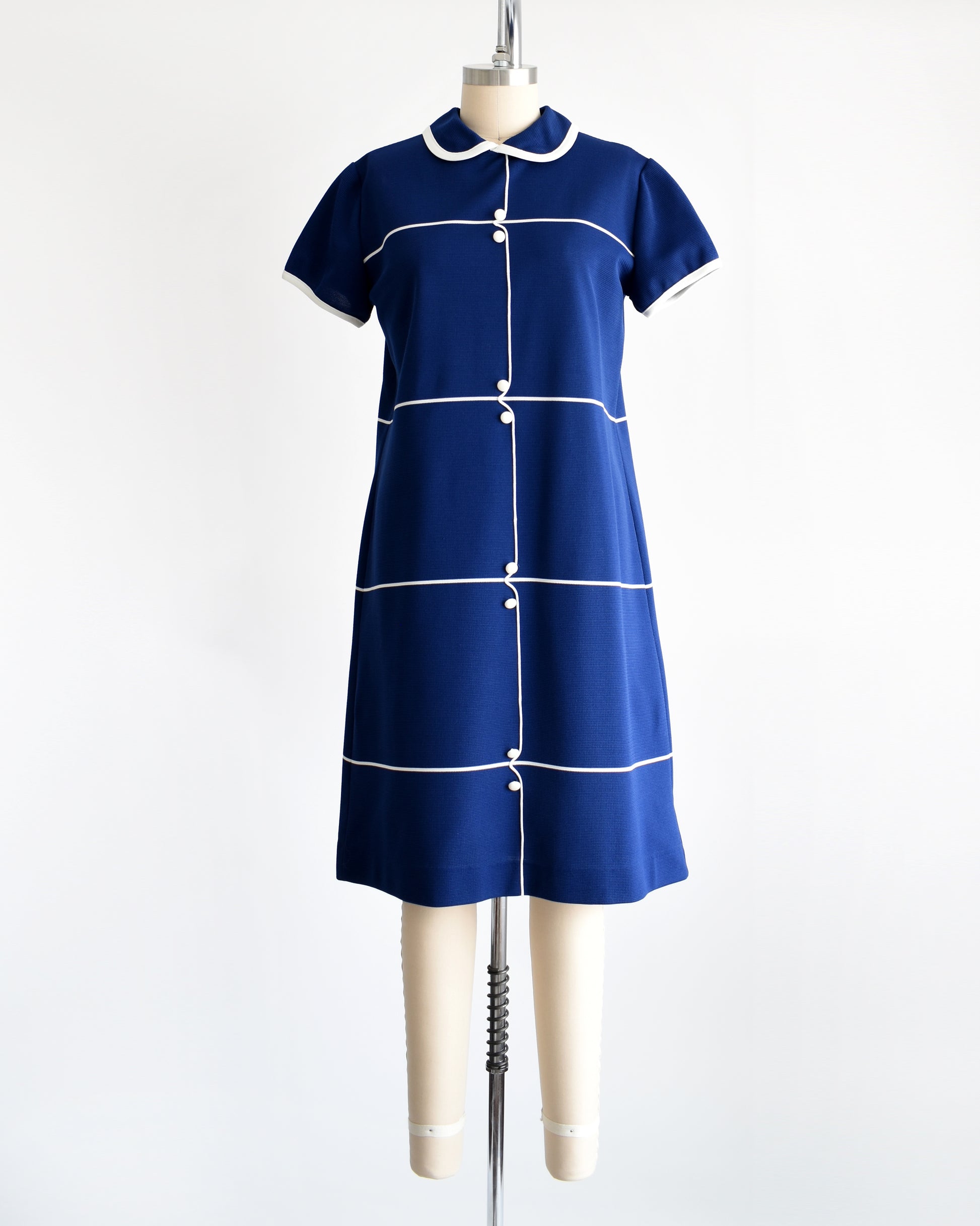 A vintage 1960s navy blue dress with horizontal white stripes, along with a stripe down the front with decorative button accents.