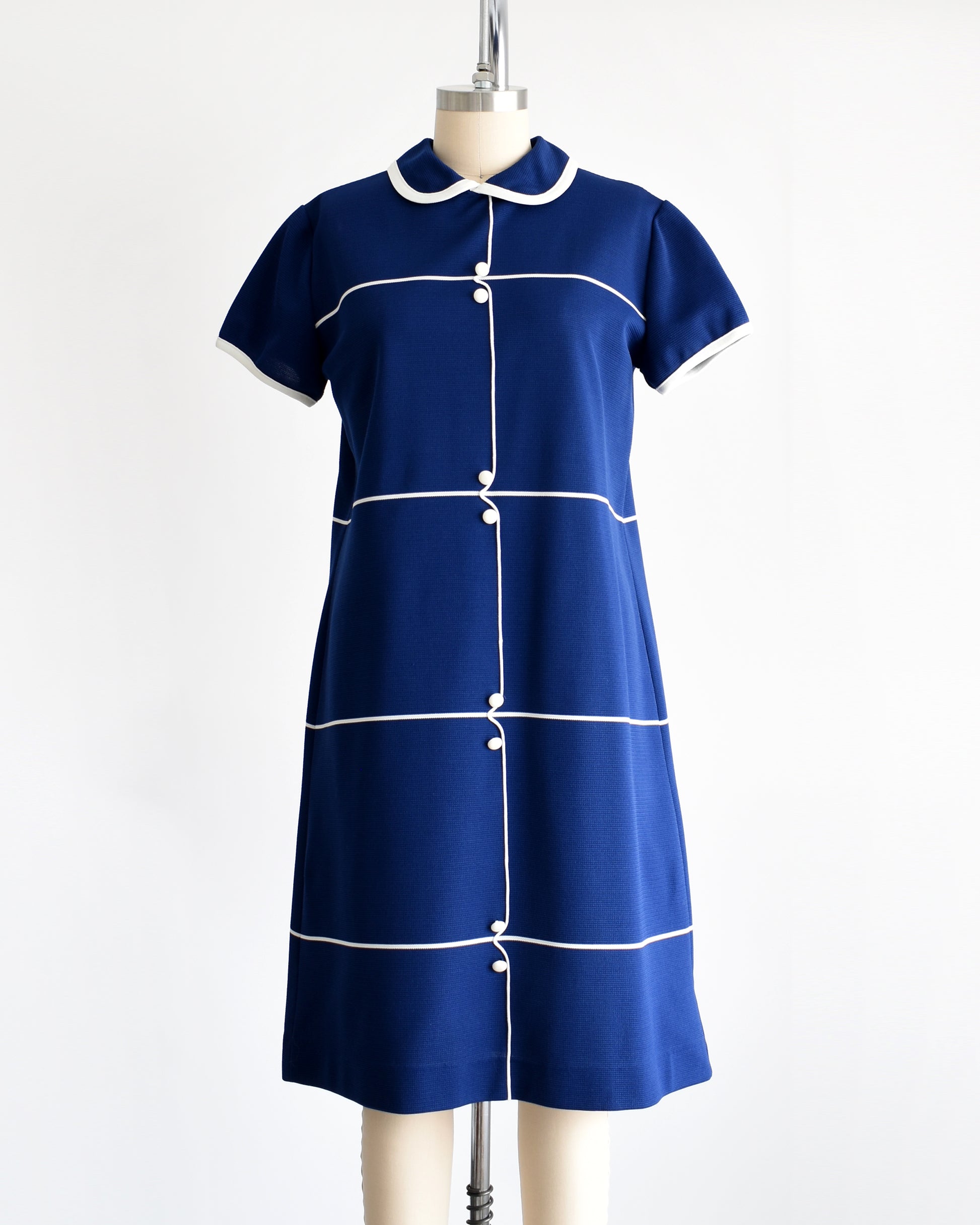 Avintage 1960s navy blue dress with horizontal white stripes, along with a stripe down the front with decorative button accents.