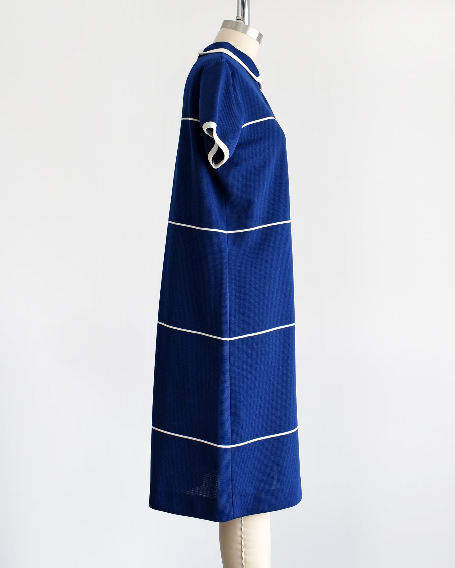 Side front view of a Avintage 1960s navy blue dress with horizontal white stripes