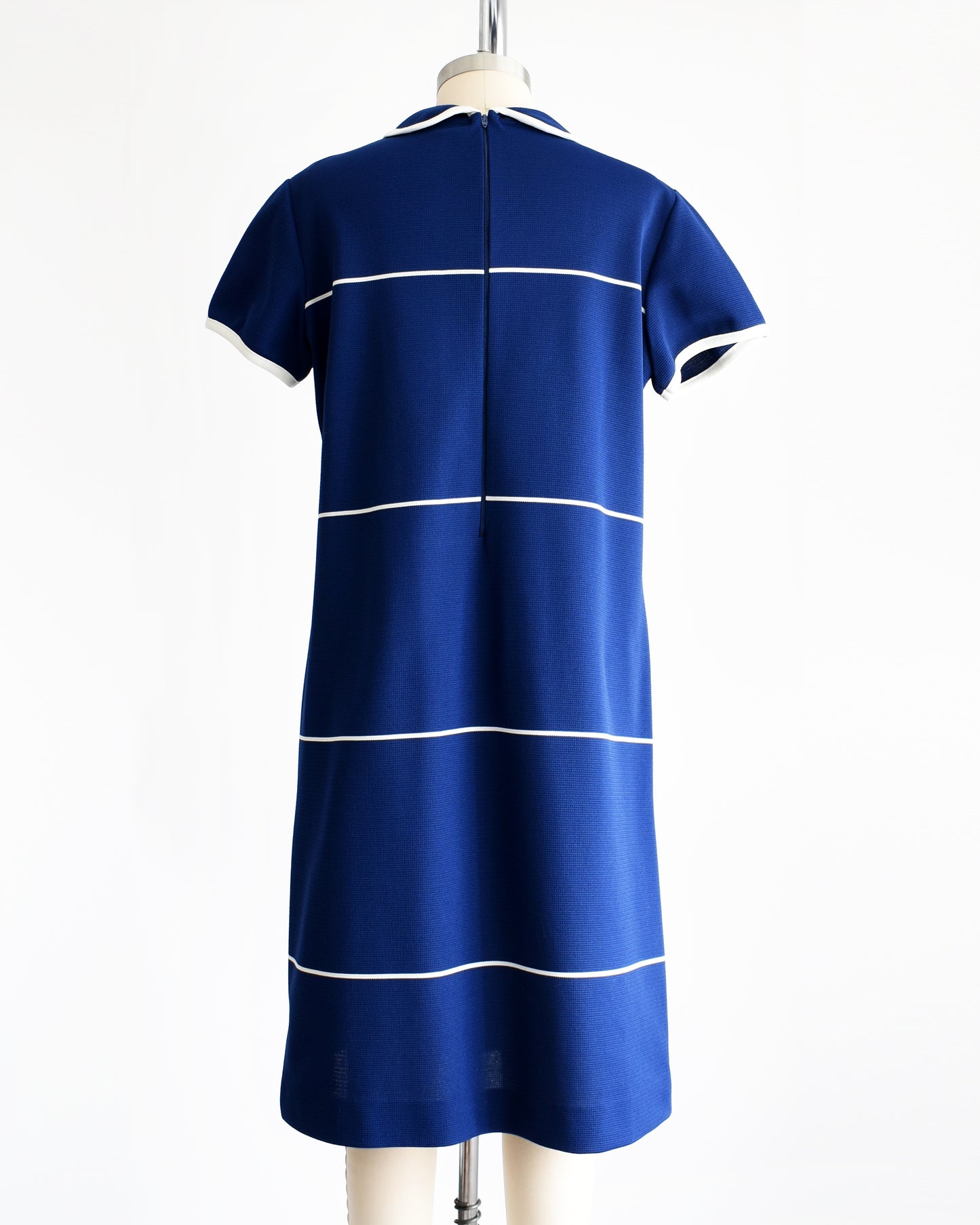 Back view of a vintage 1960s navy blue dress with horizontal white stripes and a zipper up the back
