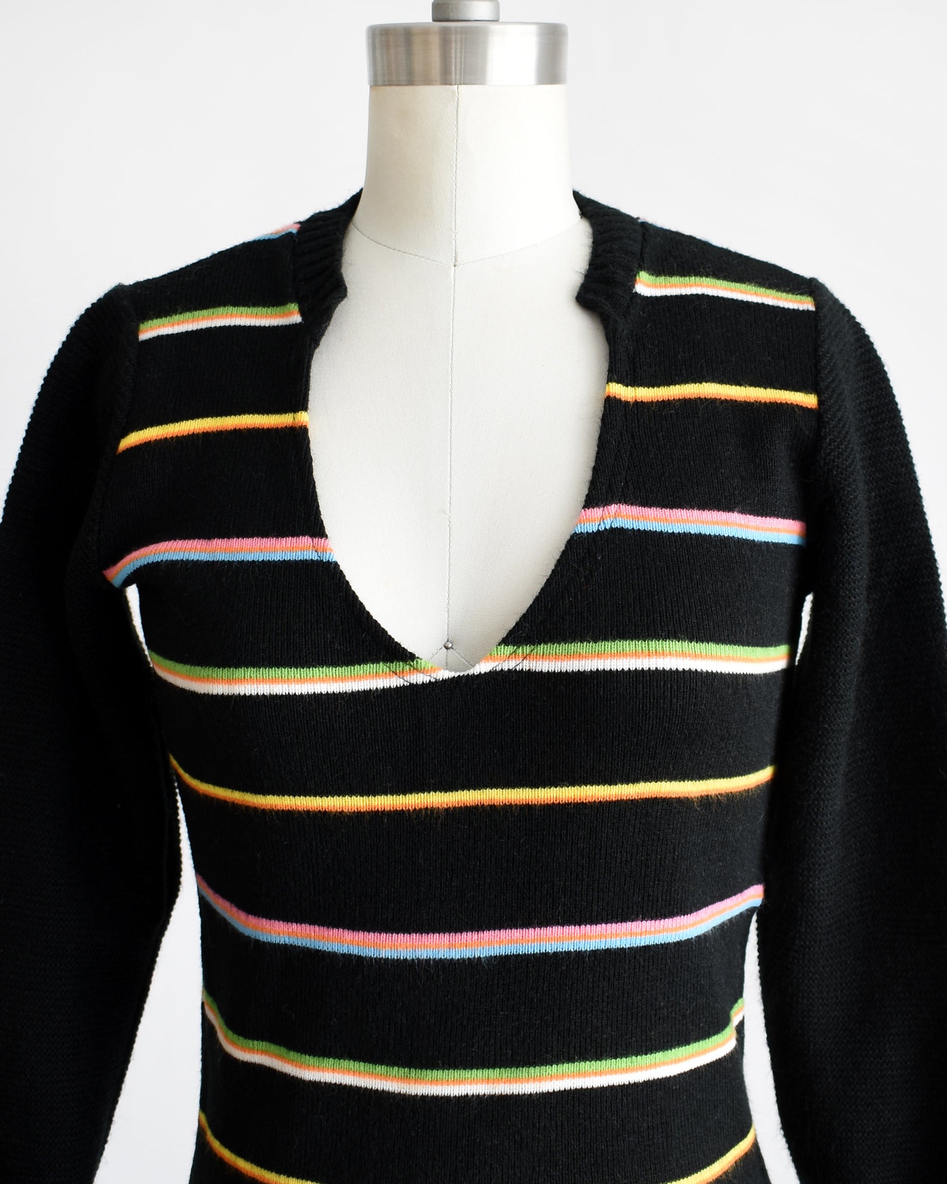 Close up of the v-neckline, black knit, and rainbow stripes