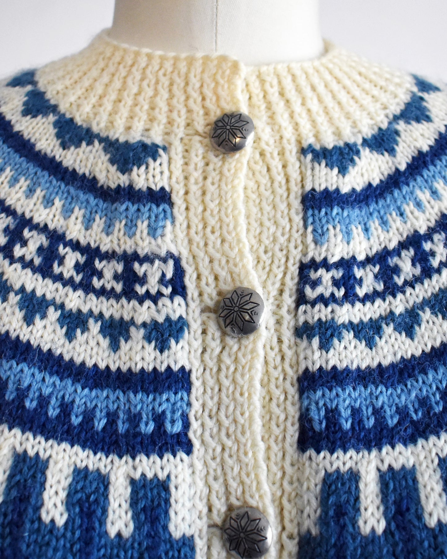 close up of a vintage 1970s Cream-colored Fair Isle sweater with blue and white pattern on a mannequin against a white background